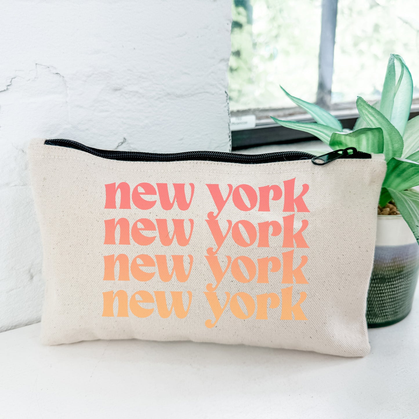 a new york pouch sitting on a table next to a potted plant