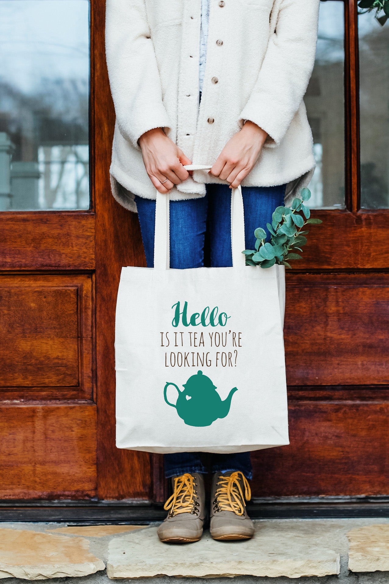 a woman holding a tea bag standing in front of a door