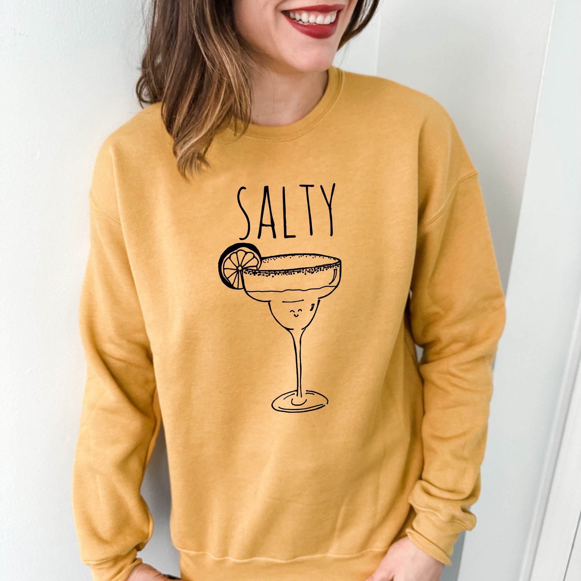 a woman wearing a yellow sweatshirt that says salty