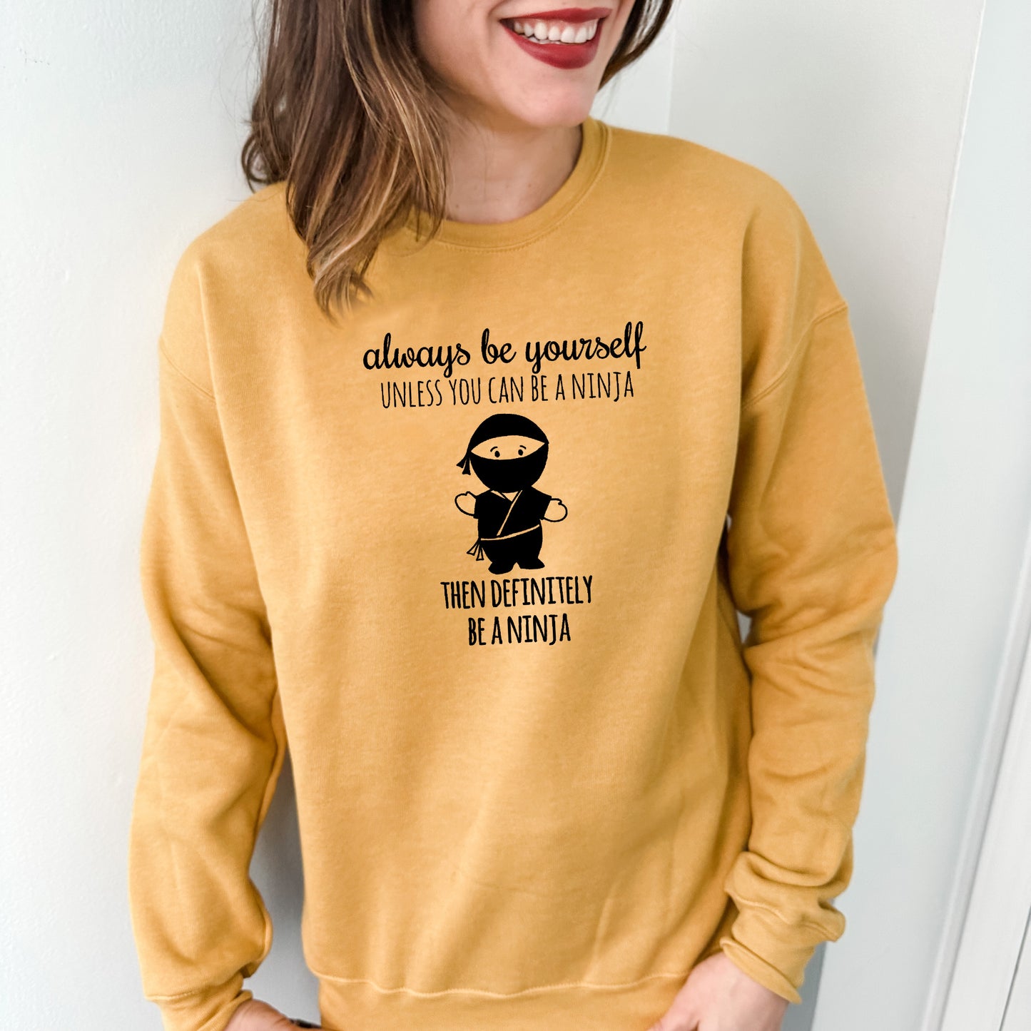 a woman wearing a yellow sweatshirt that says, always be yourself unless you can be