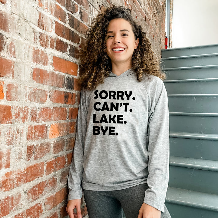 a woman leaning against a brick wall wearing a sweatshirt that says sorry can't