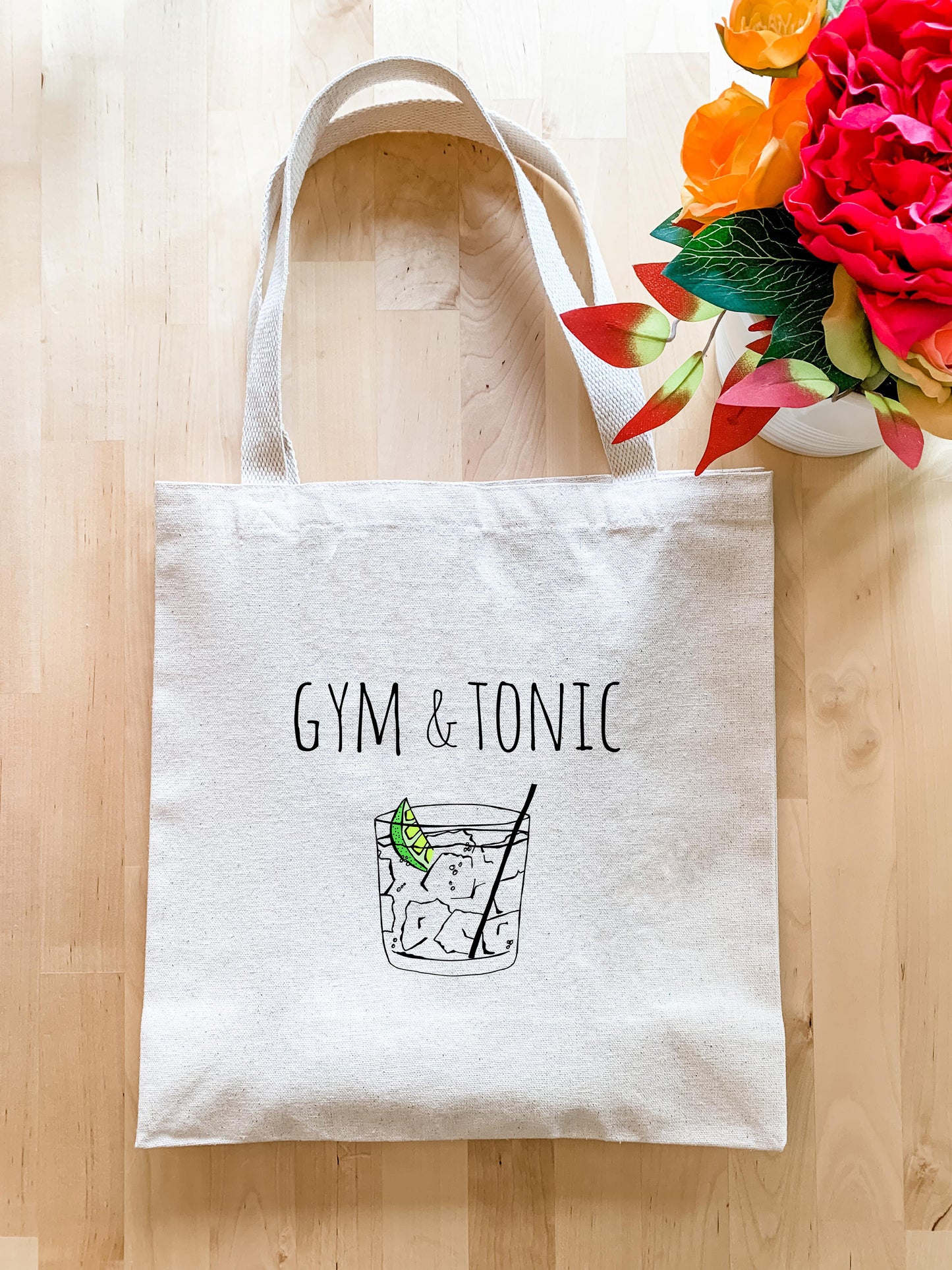 a gym and tonic bag next to a vase of flowers
