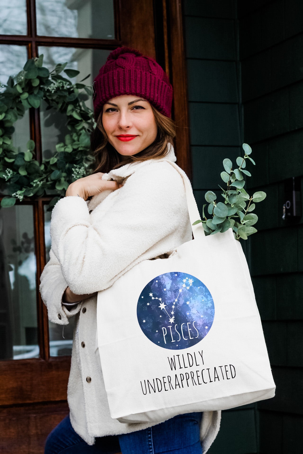 a woman carrying a white bag with the zodiac sign on it