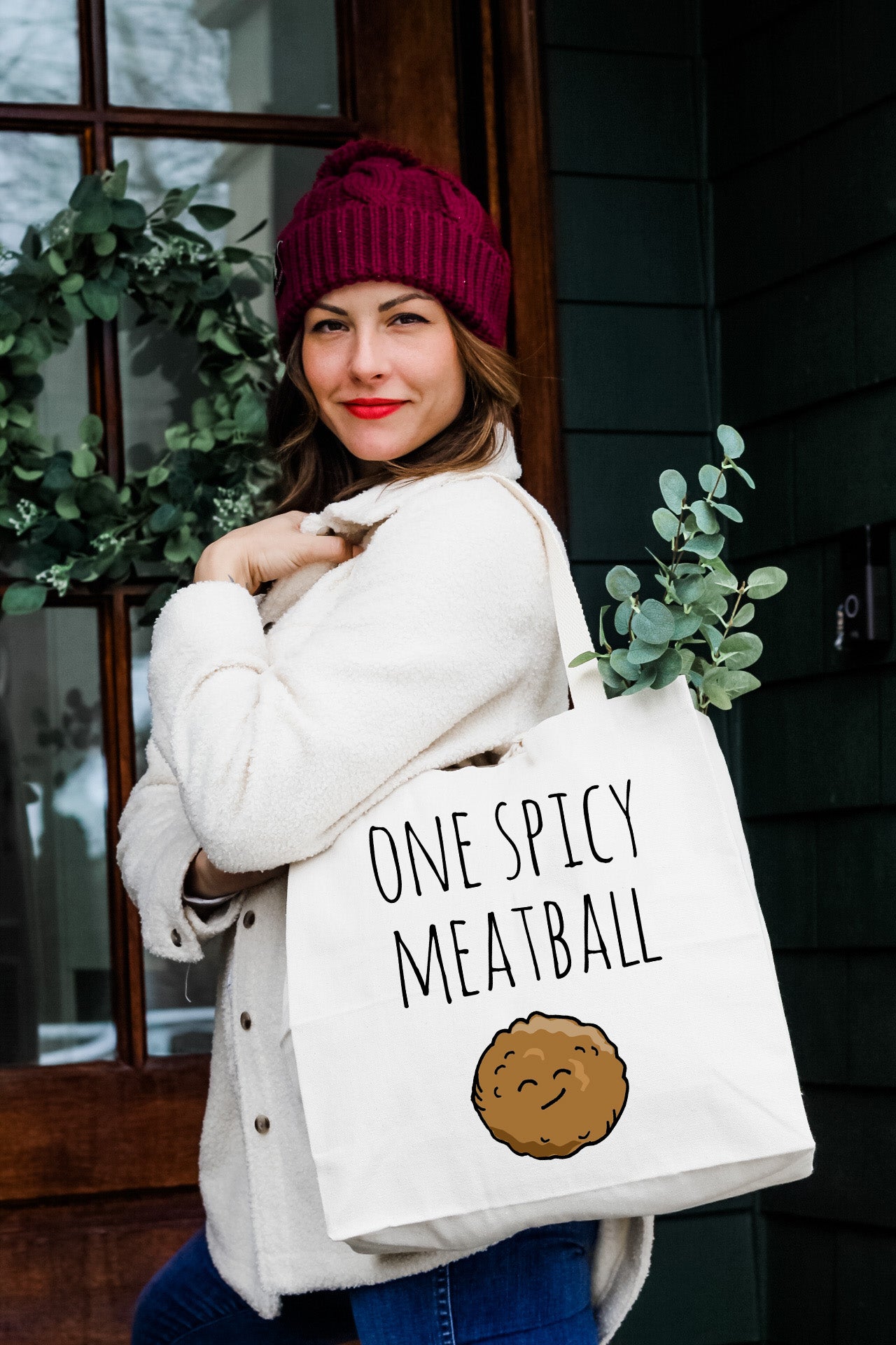 a woman holding a bag that says one spicy meatball