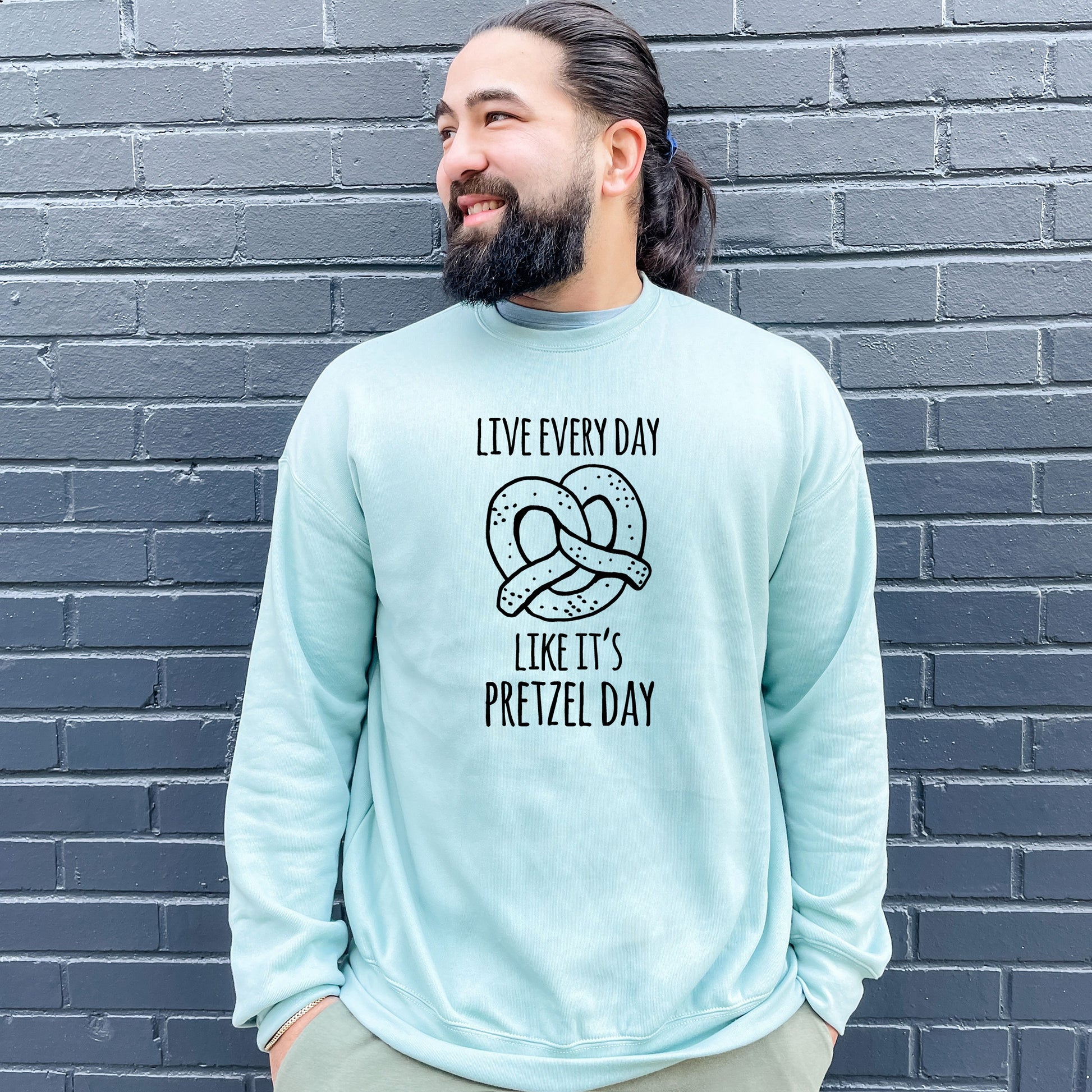 a man with a beard wearing a blue sweatshirt with a pretzel on it