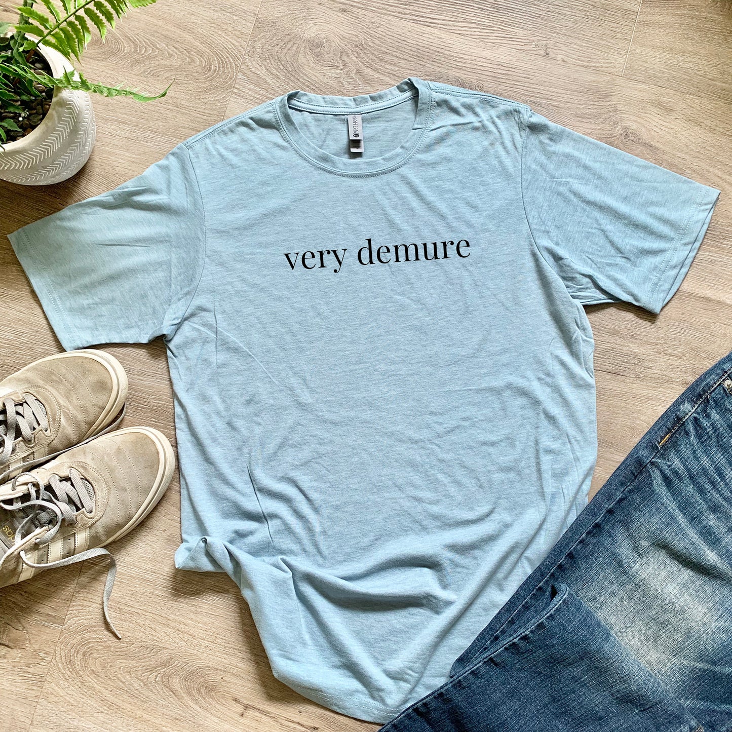 a t - shirt that says very demure next to a pair of jeans