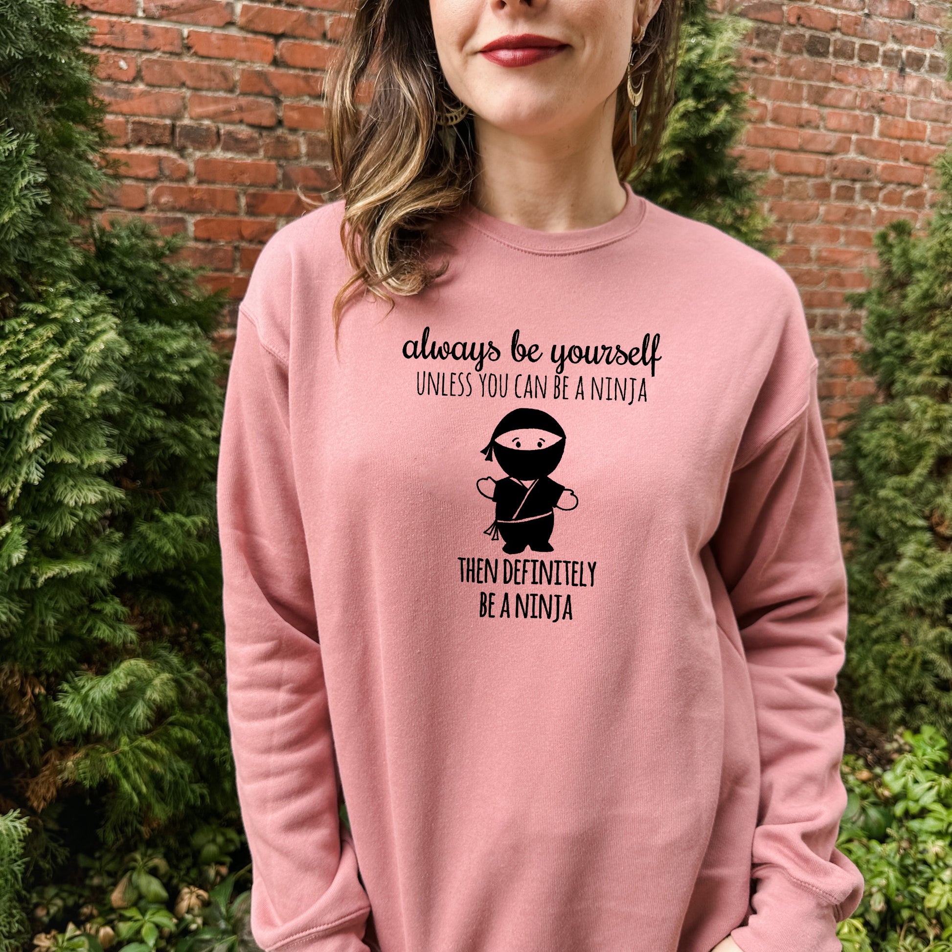 a woman wearing a pink sweatshirt that says, always be yourself unless you can be