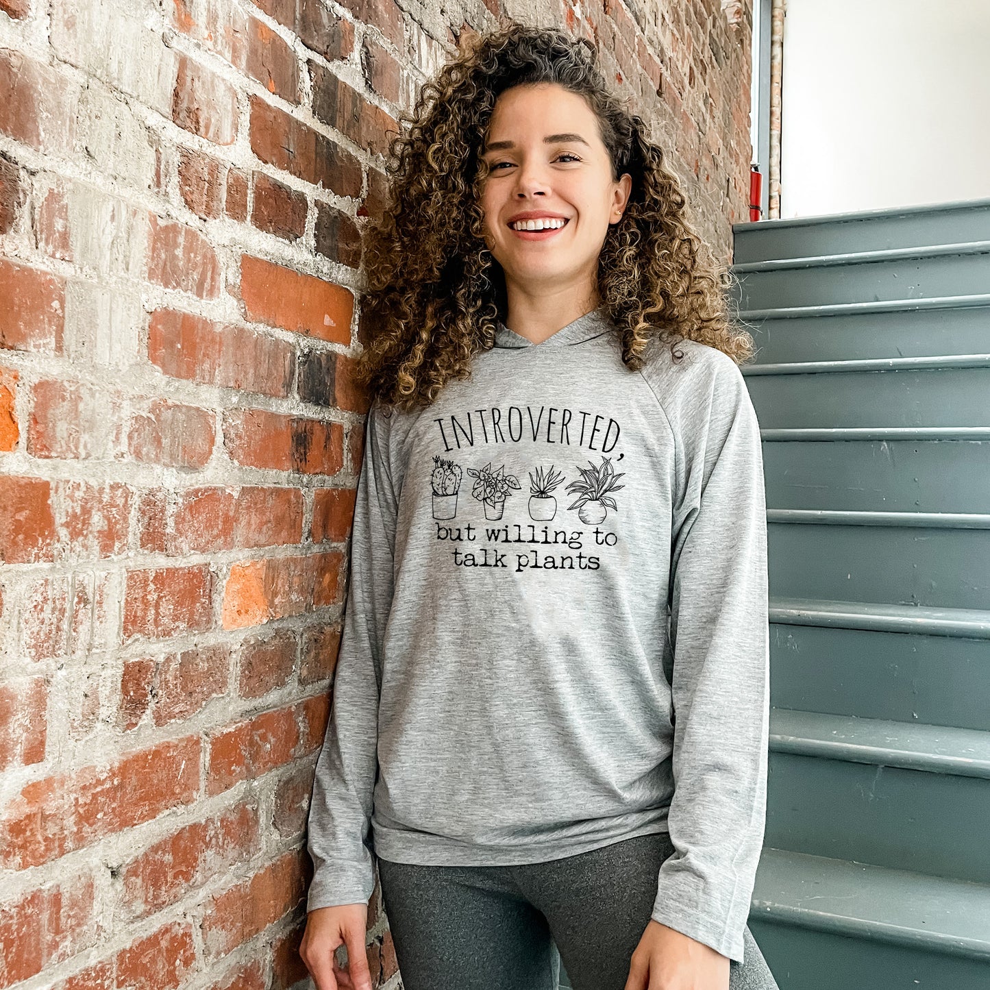 a woman standing next to a brick wall