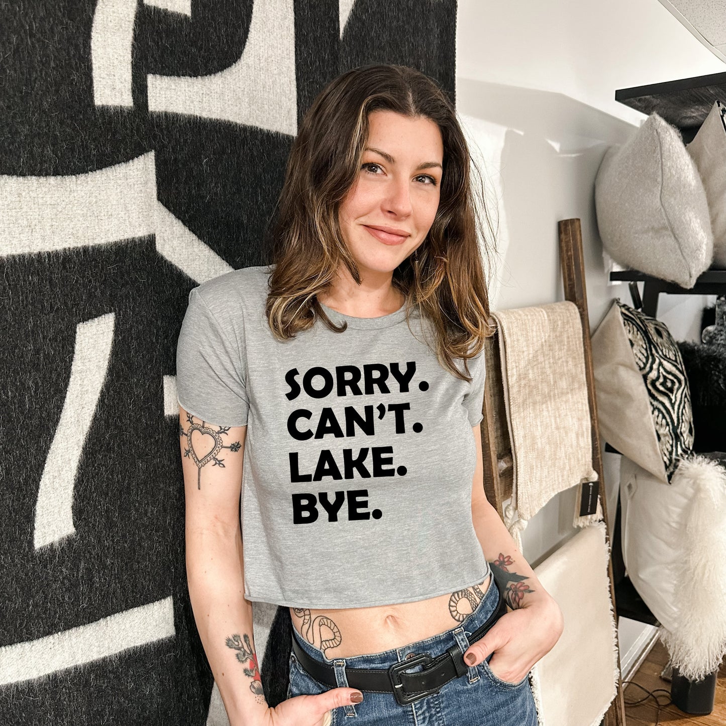 a woman standing in front of a wall wearing a t - shirt that says sorry