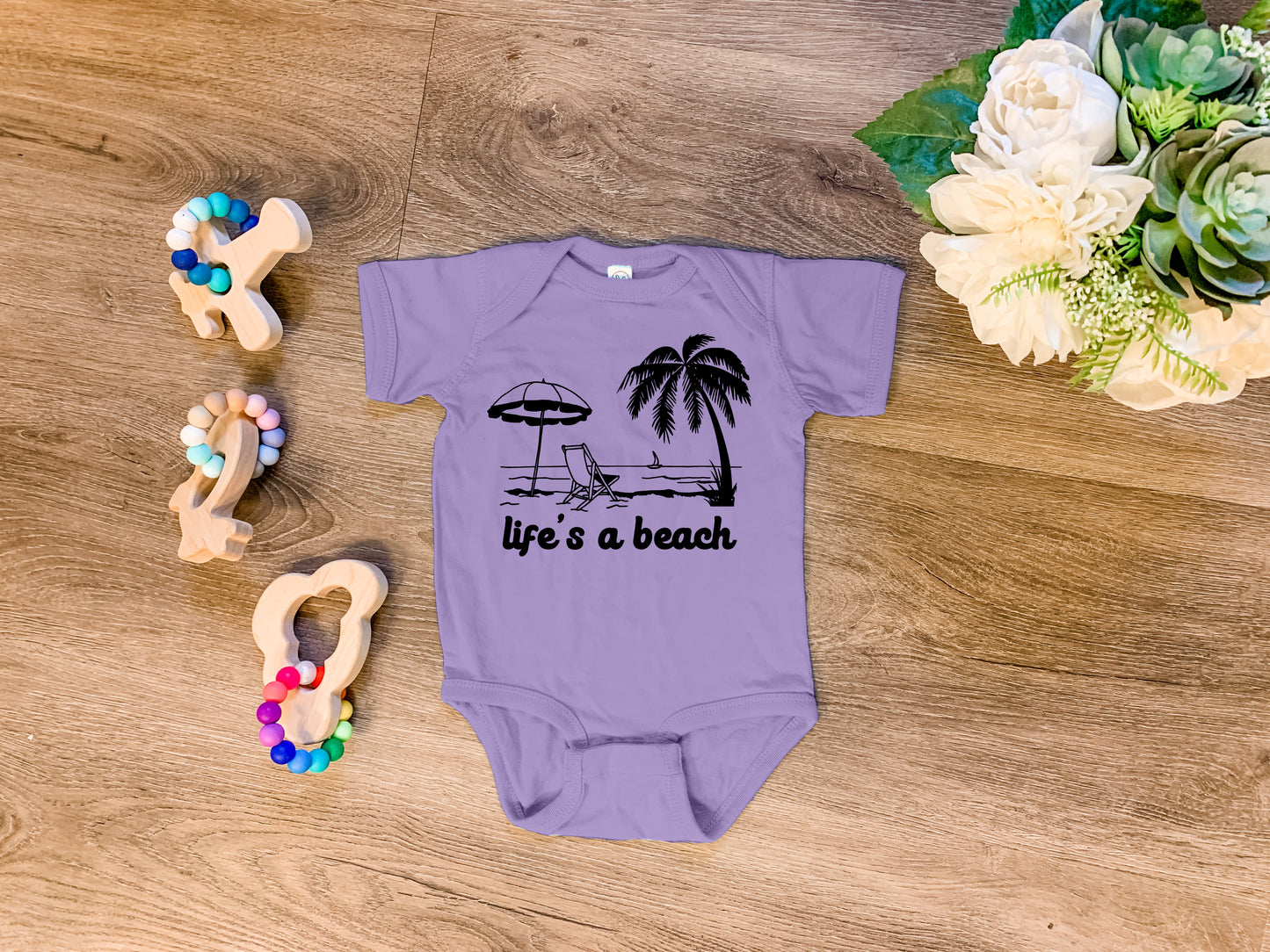 a baby bodysuit that says life's a beach next to a pair of