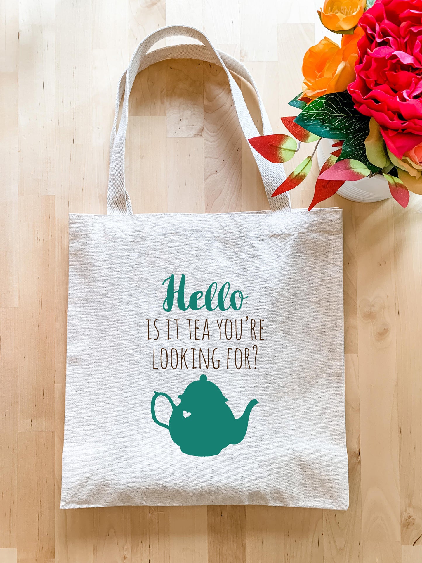 a tea bag with a teapot on it next to a vase of flowers