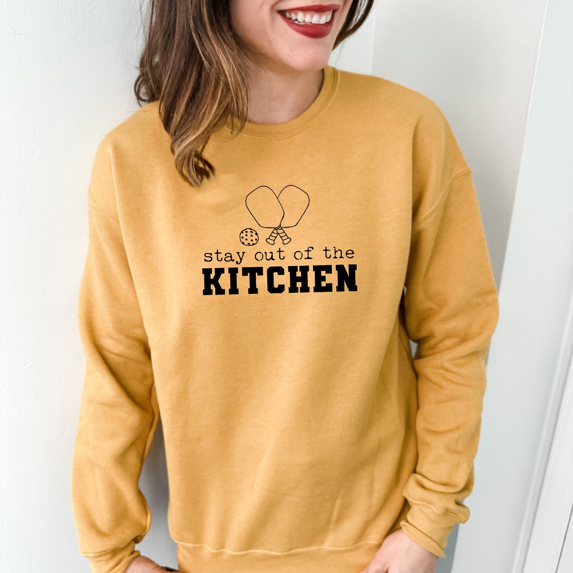 a woman wearing a sweatshirt that says stay out of the kitchen