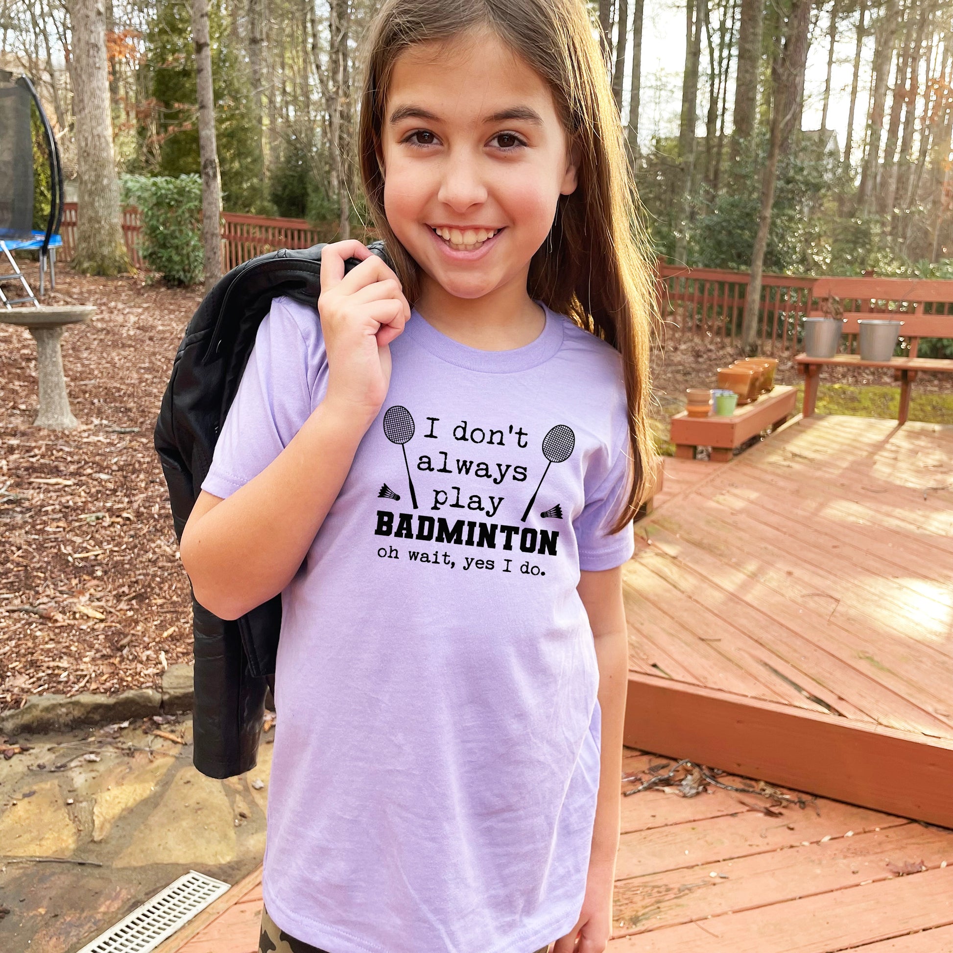 a young girl holding a backpack and smiling