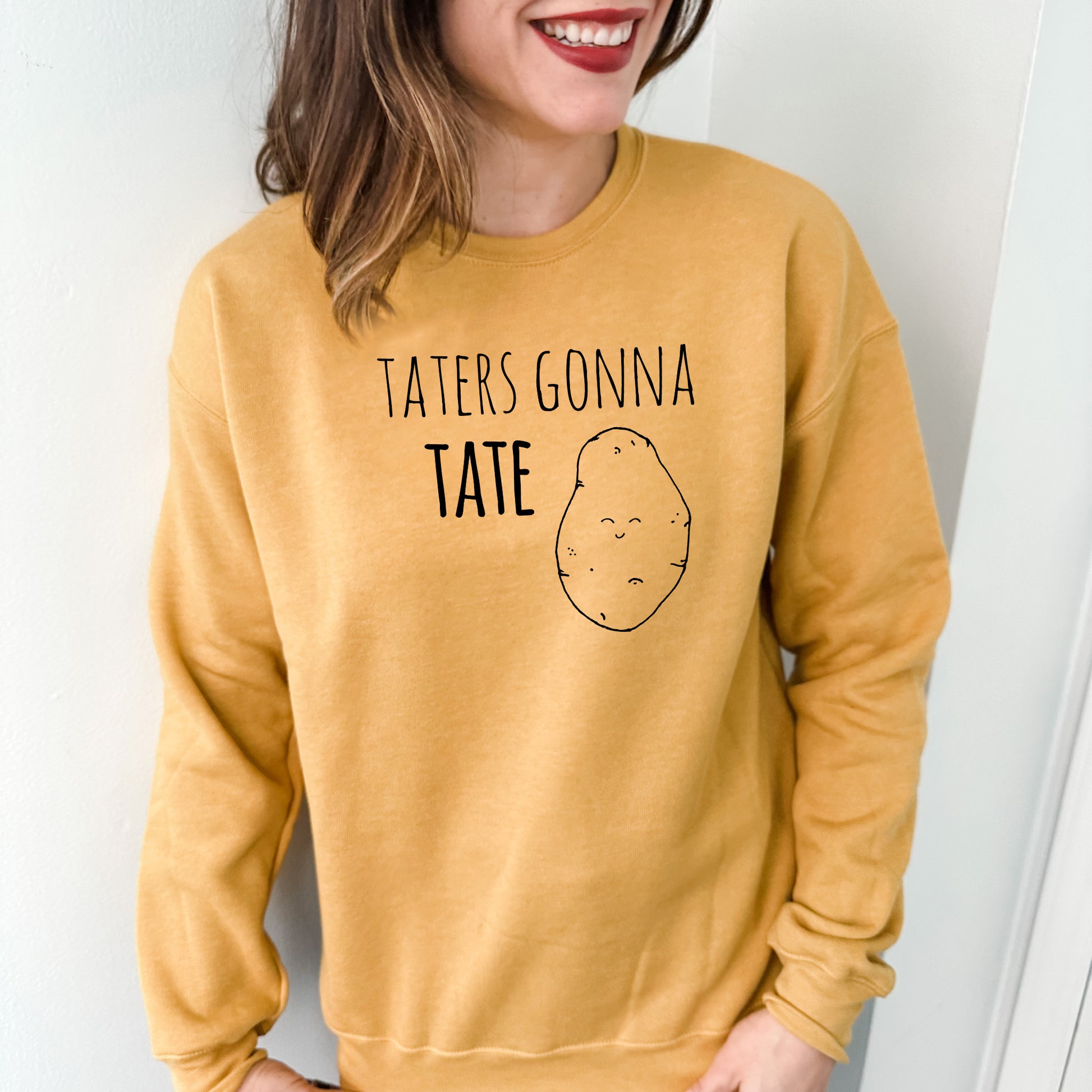 a woman wearing a yellow sweater that says tater's gonna tater