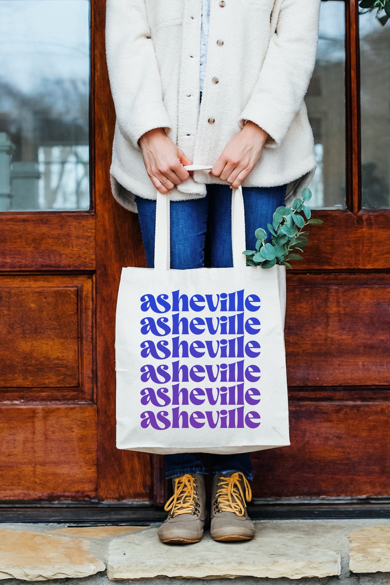 a woman holding a tote bag in front of a door