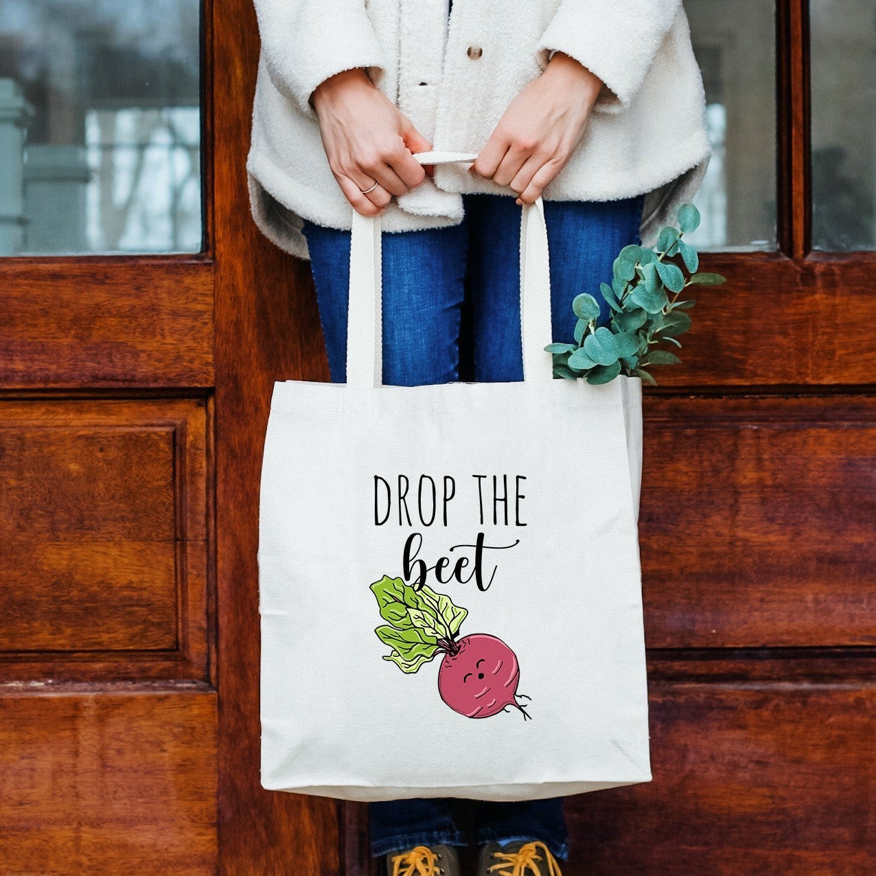 a woman holding a bag that says drop the beet