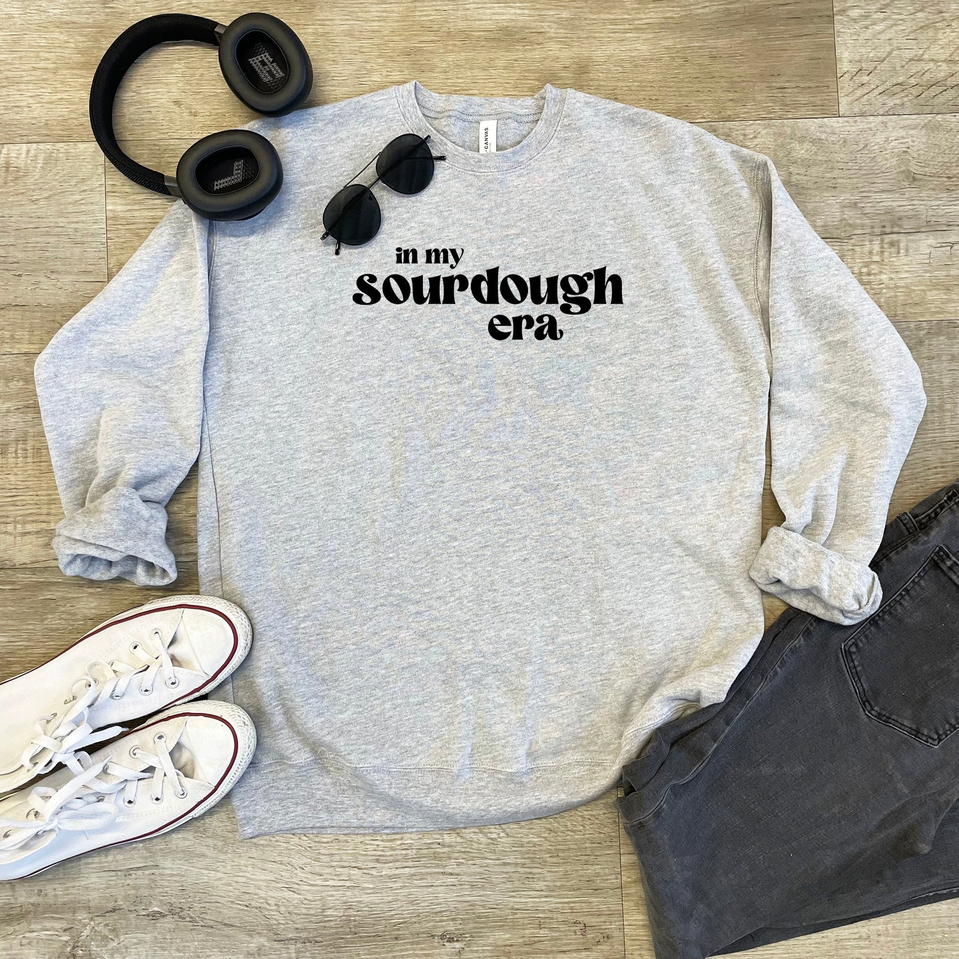 a sweatshirt that says in my sourdough era next to headphones