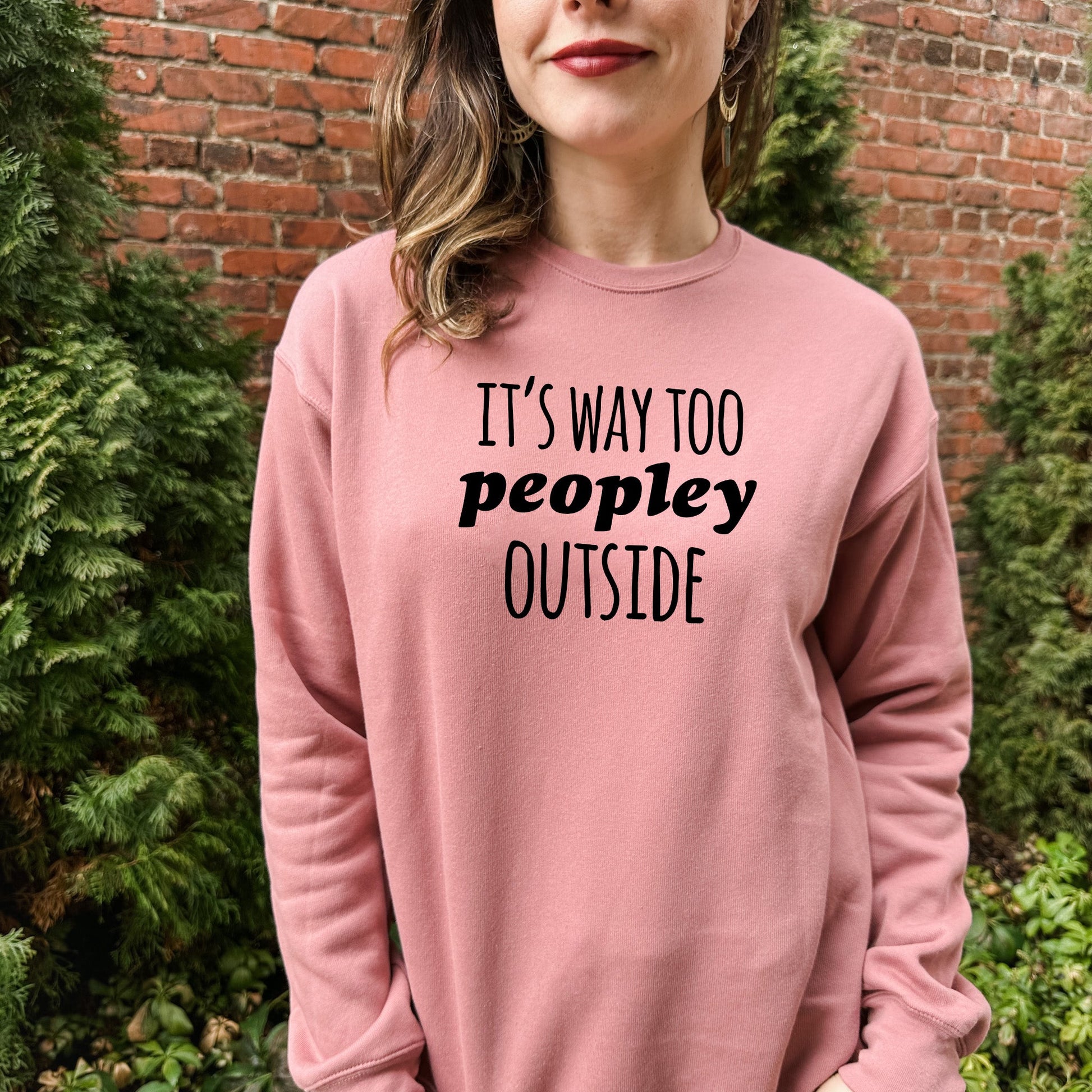 a woman wearing a pink sweatshirt that says it's way too peopley outside