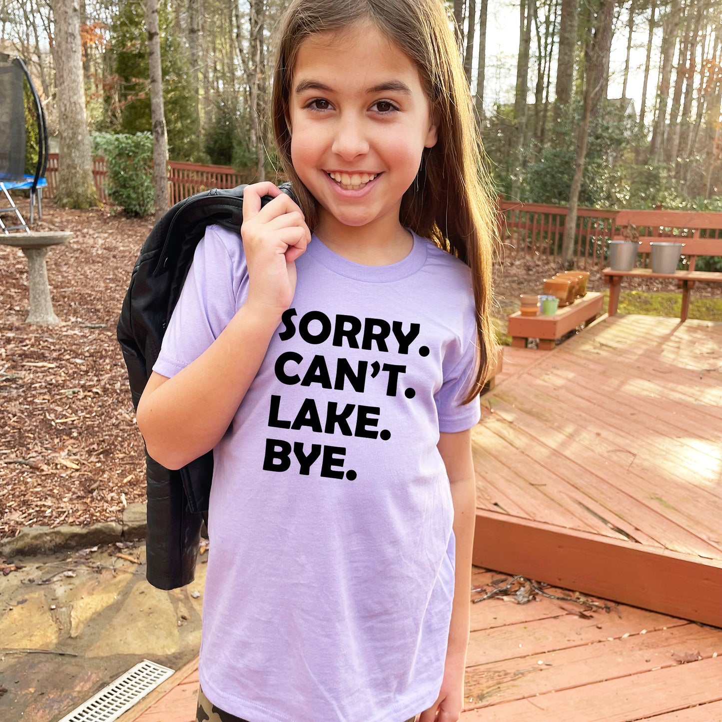 a young girl holding a backpack and wearing a t - shirt that says sorry can