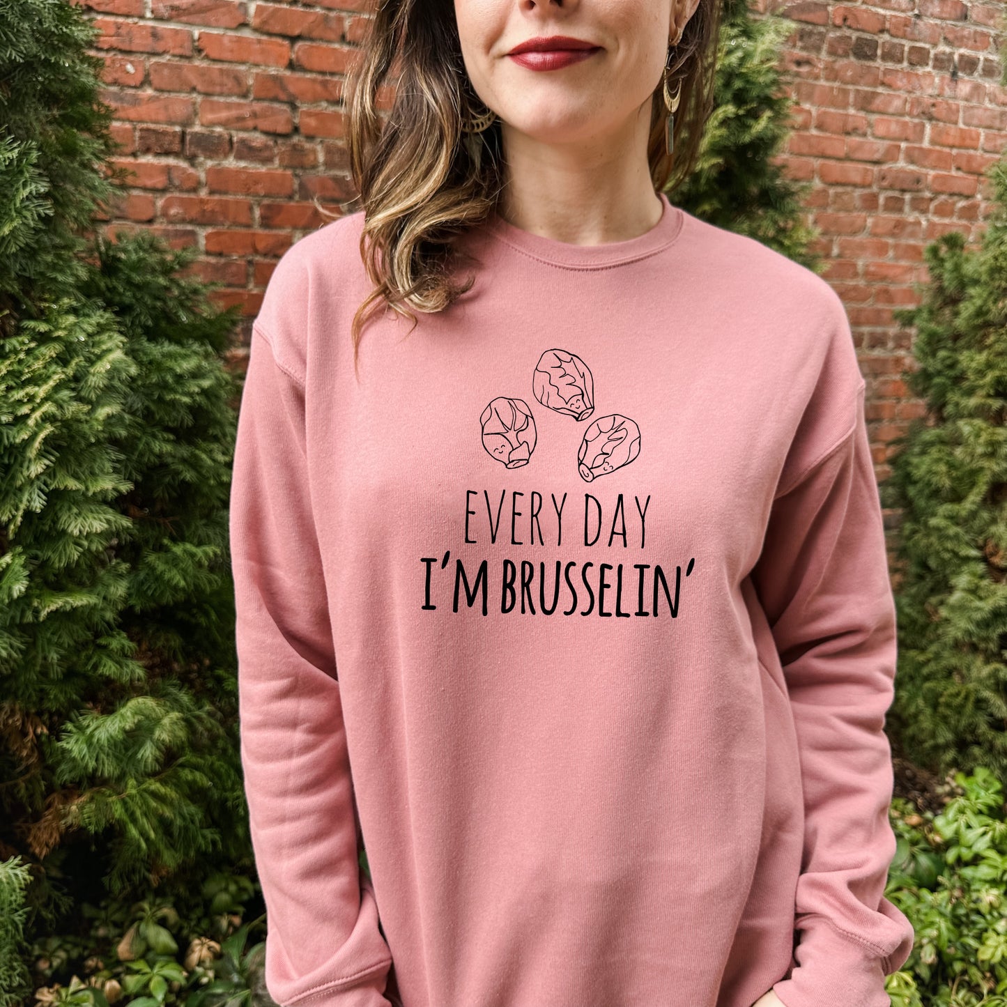 a woman wearing a pink sweatshirt that says every day i'm brussein