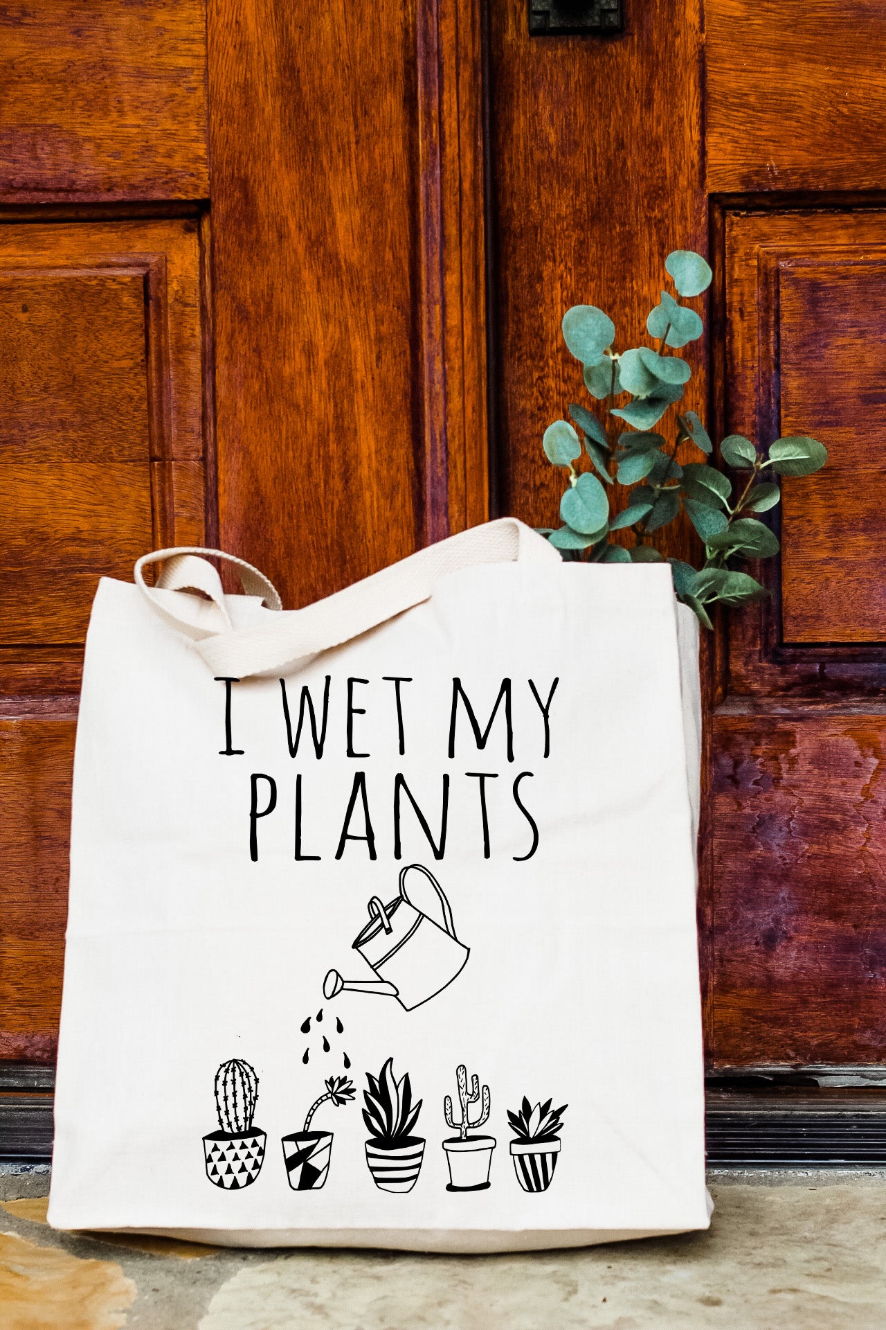 a white tote bag sitting on top of a wooden door