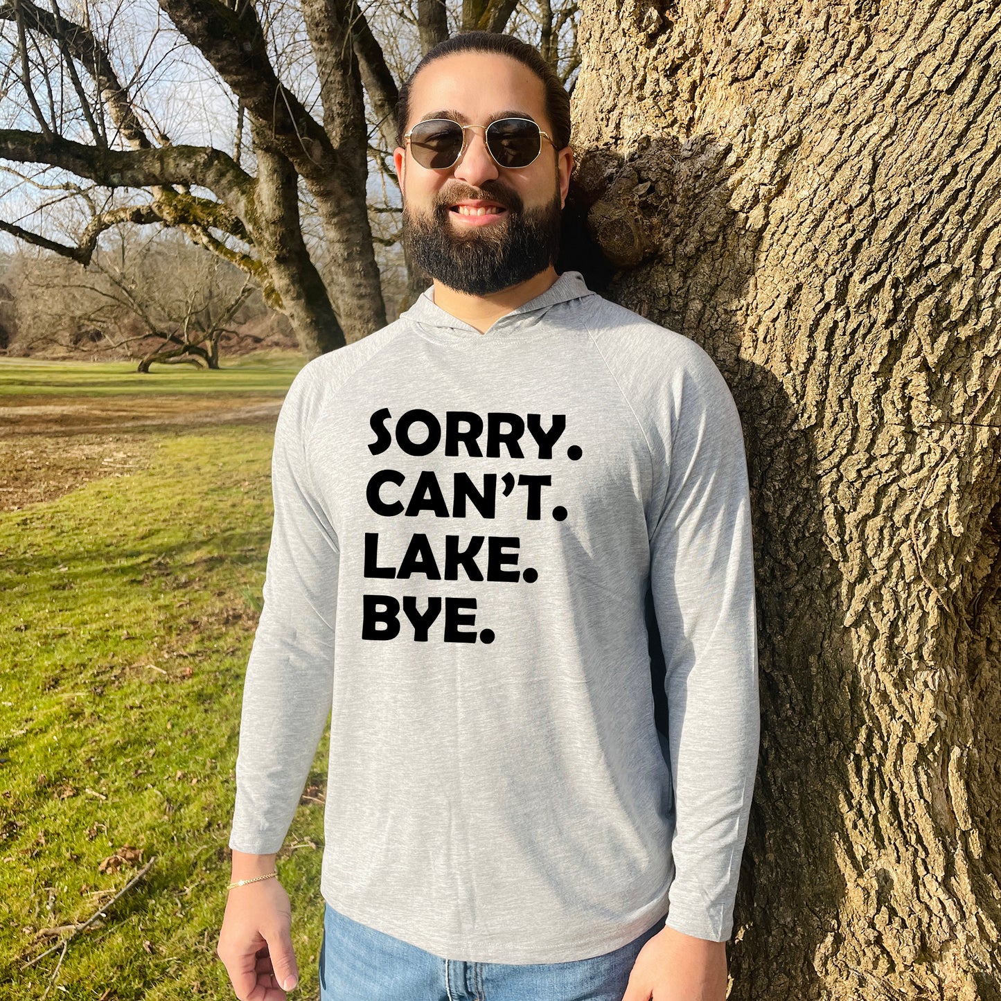 a man standing next to a tree wearing a shirt that says sorry, can '