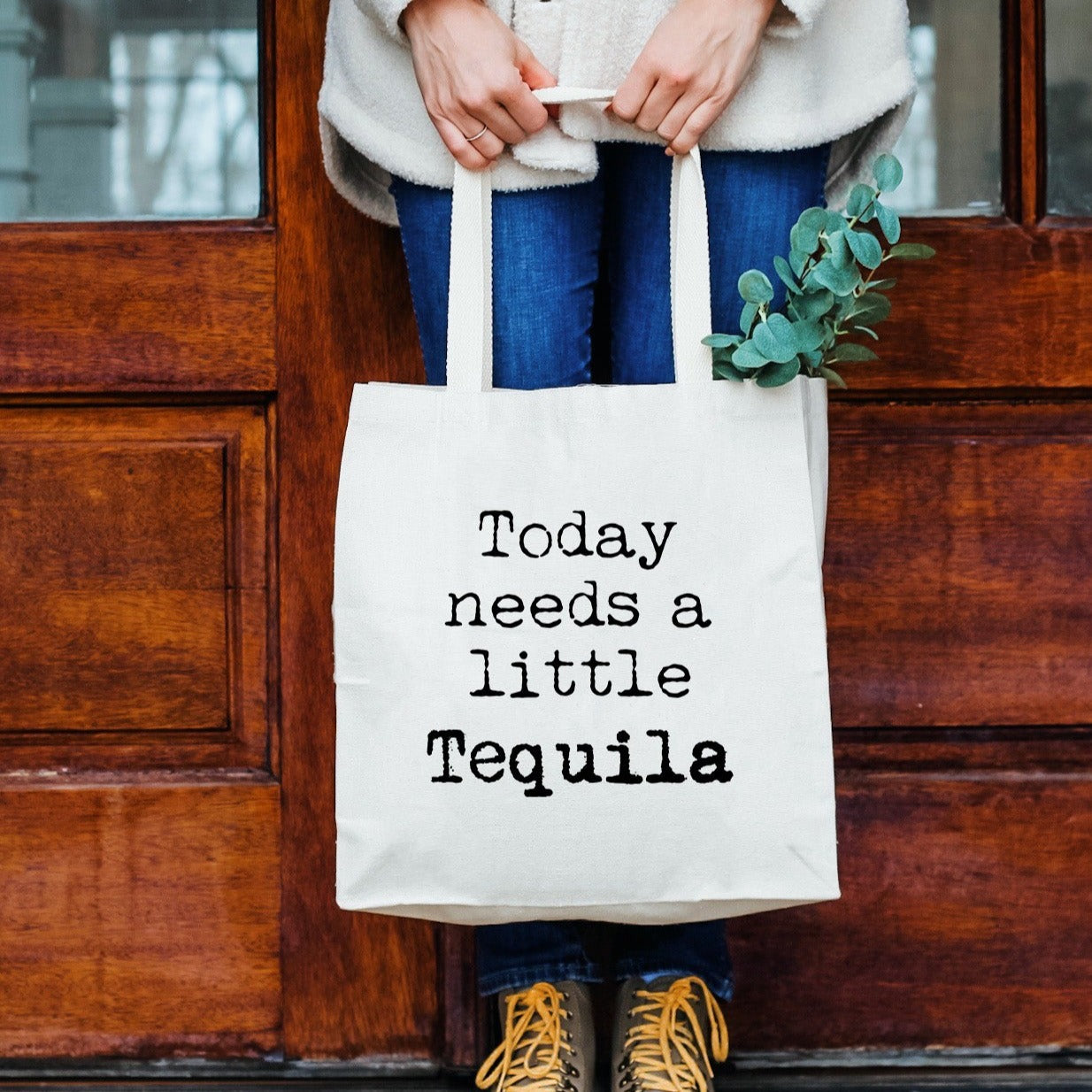 a woman holding a bag that says today needs a little tequila