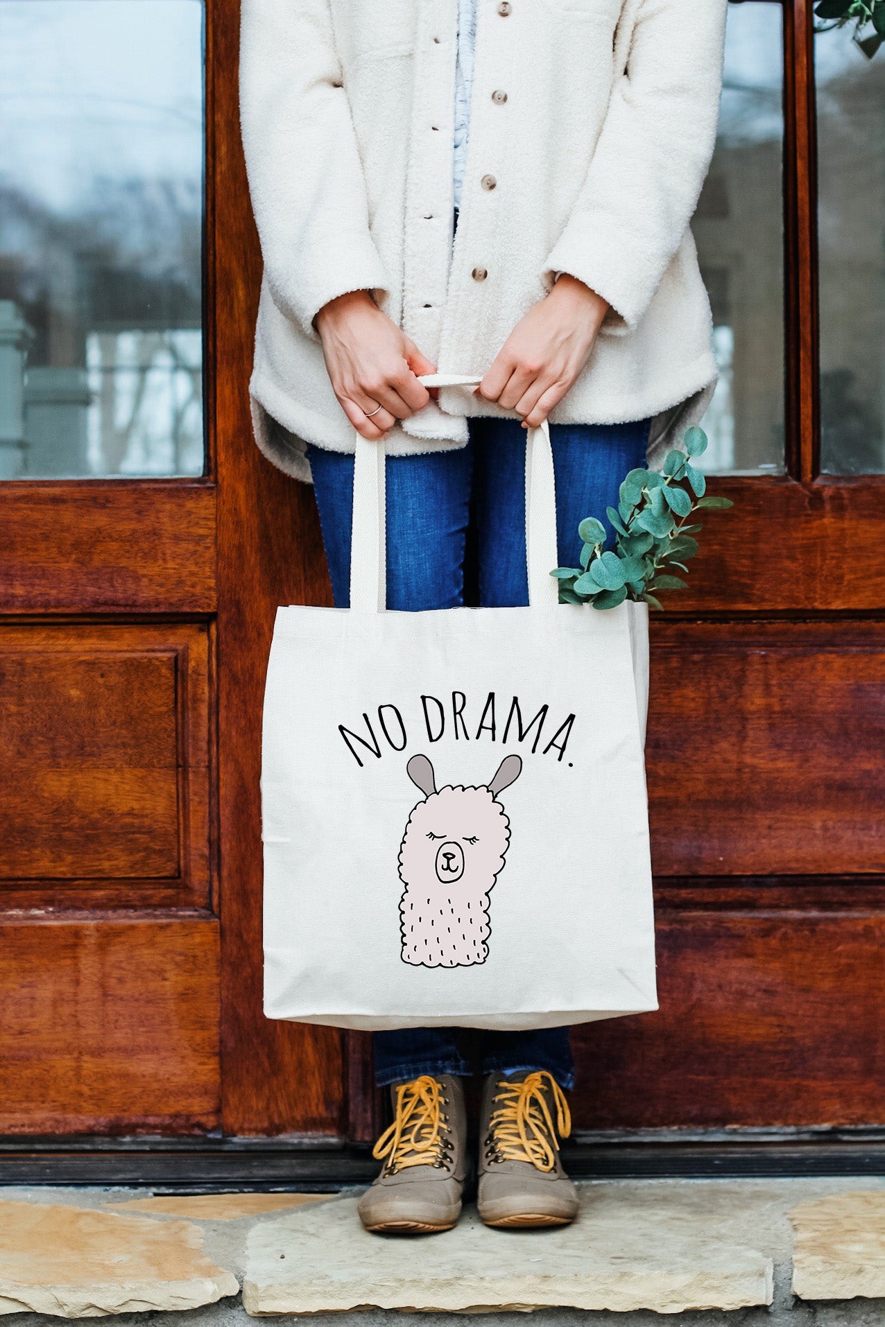 a woman holding a no drama llama tote bag