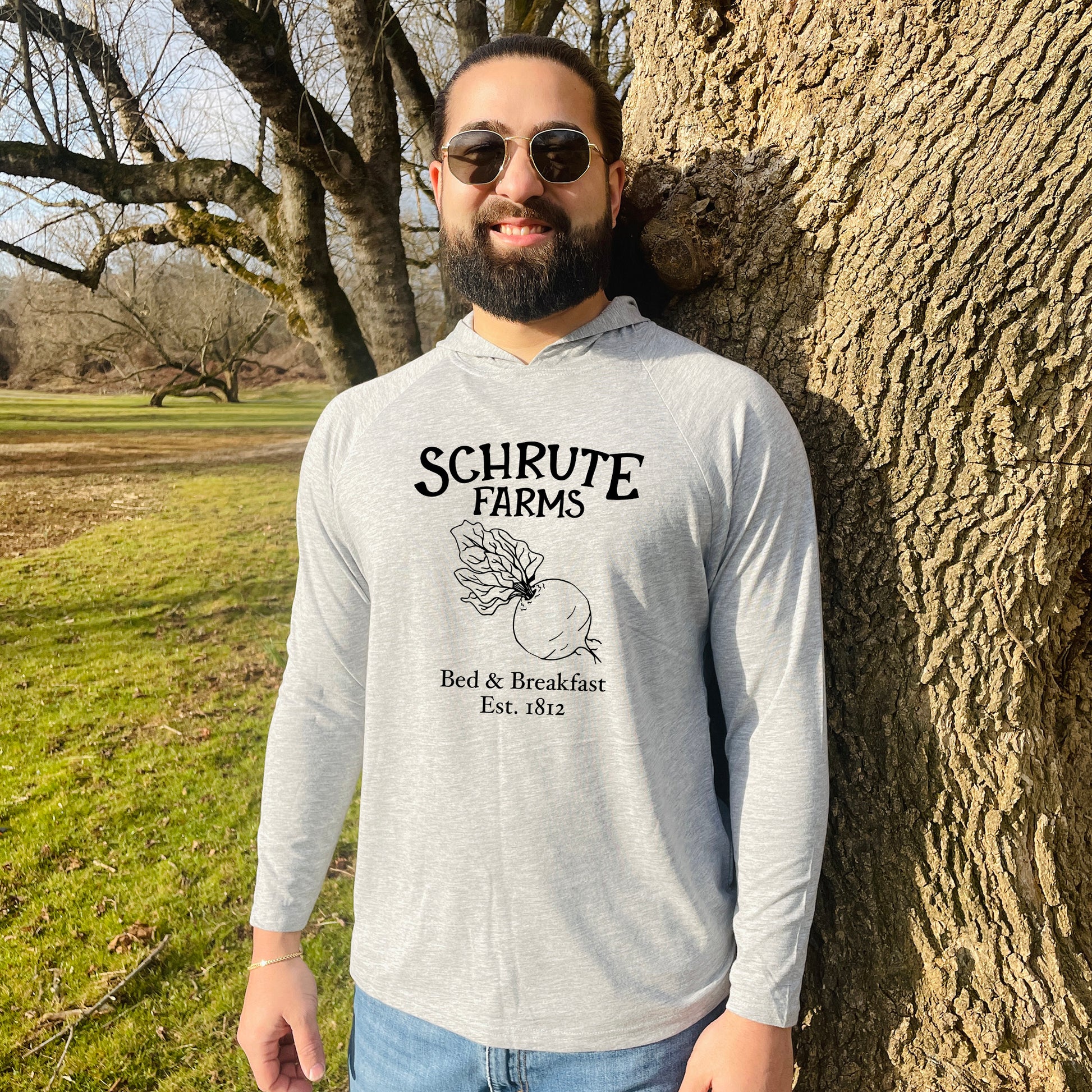 a man standing next to a tree in a field