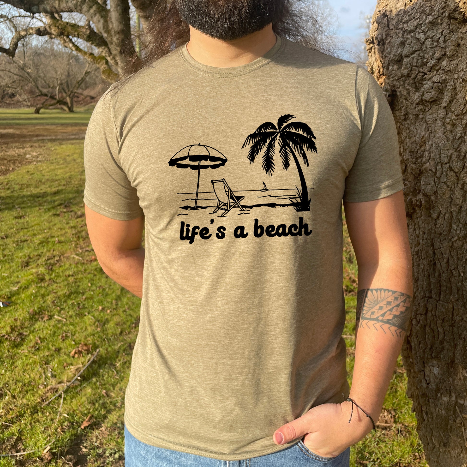 a man standing next to a tree wearing a t - shirt