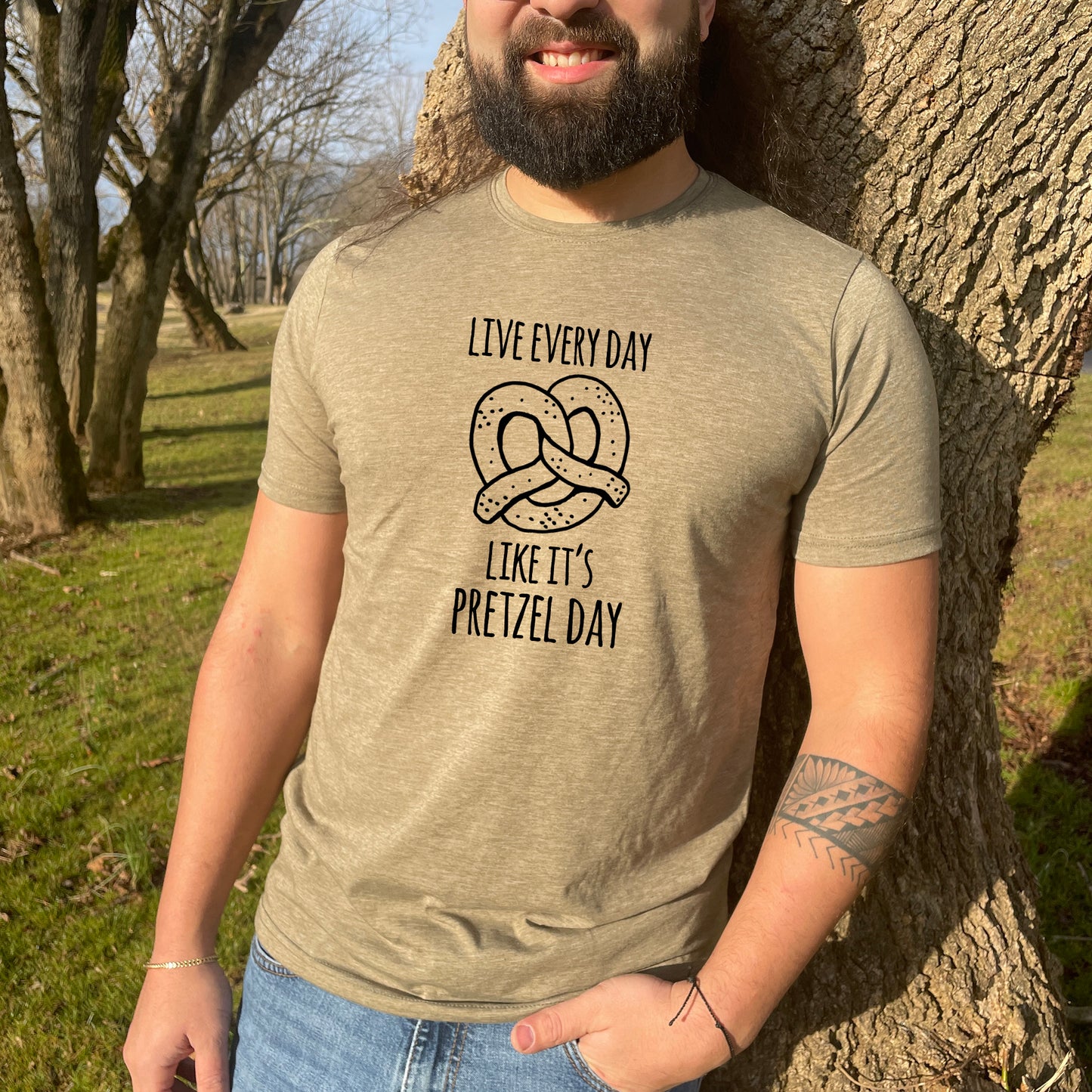 a man standing next to a tree wearing a t - shirt