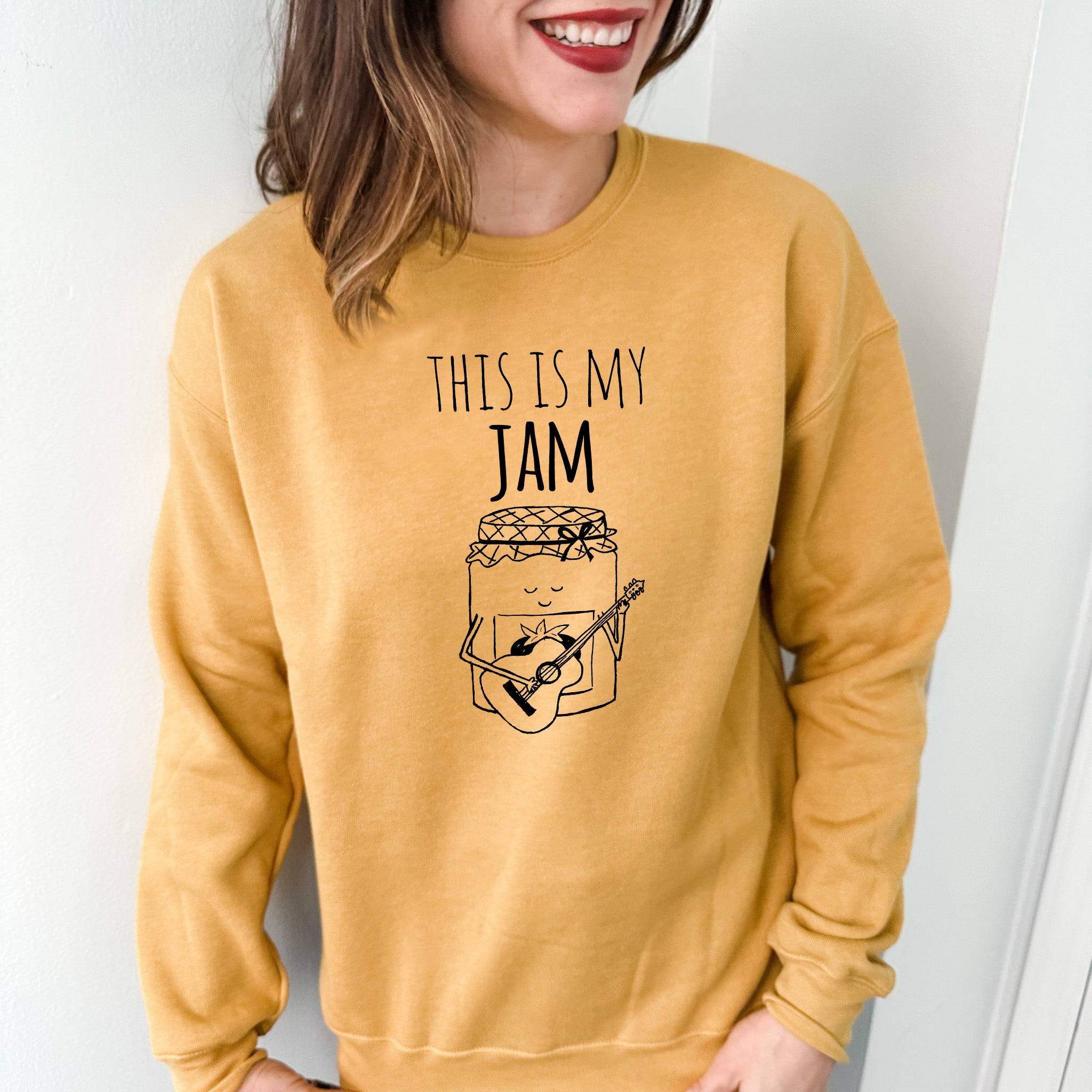 a woman wearing a yellow sweatshirt with a jar of jam on it