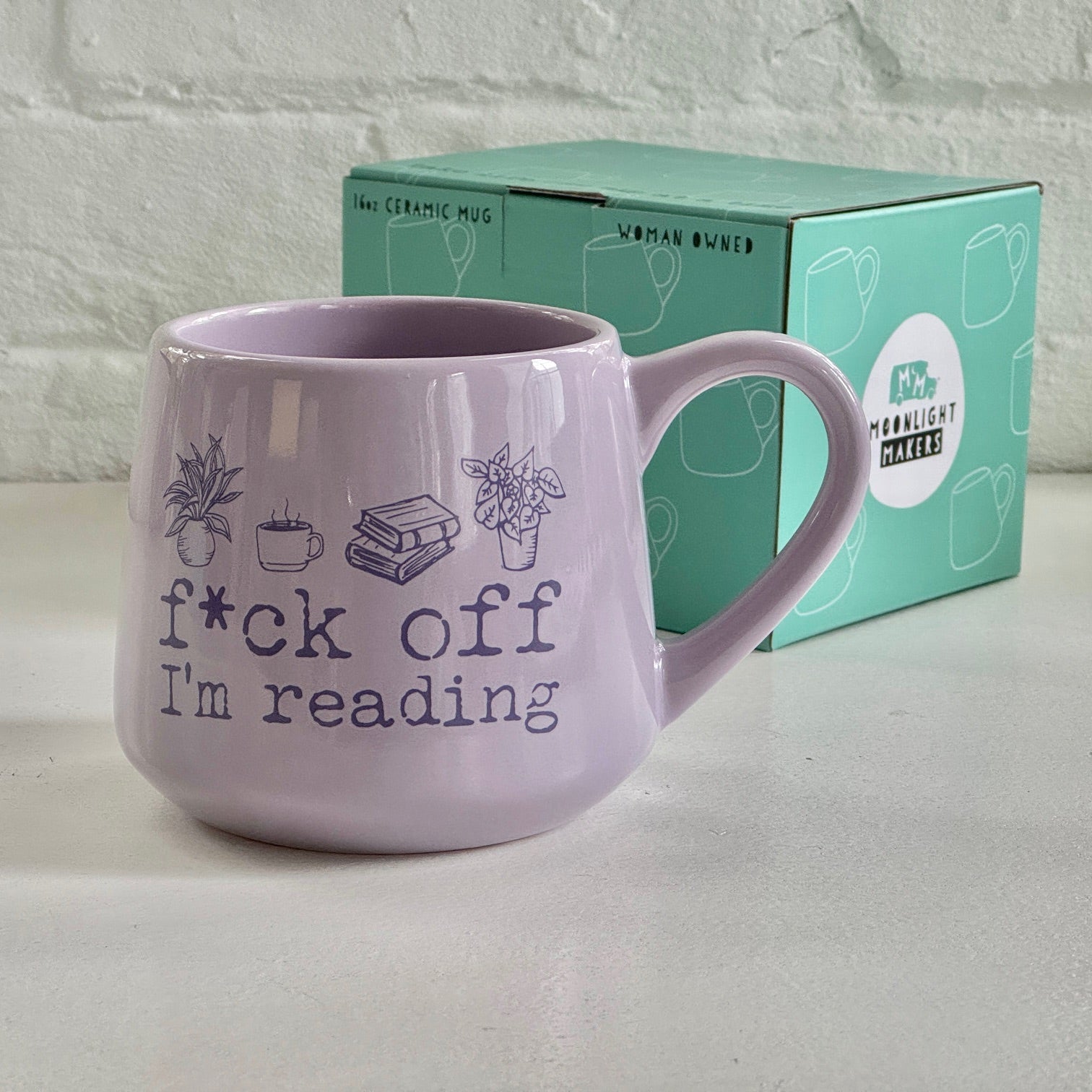 a purple coffee mug sitting next to a box of tea