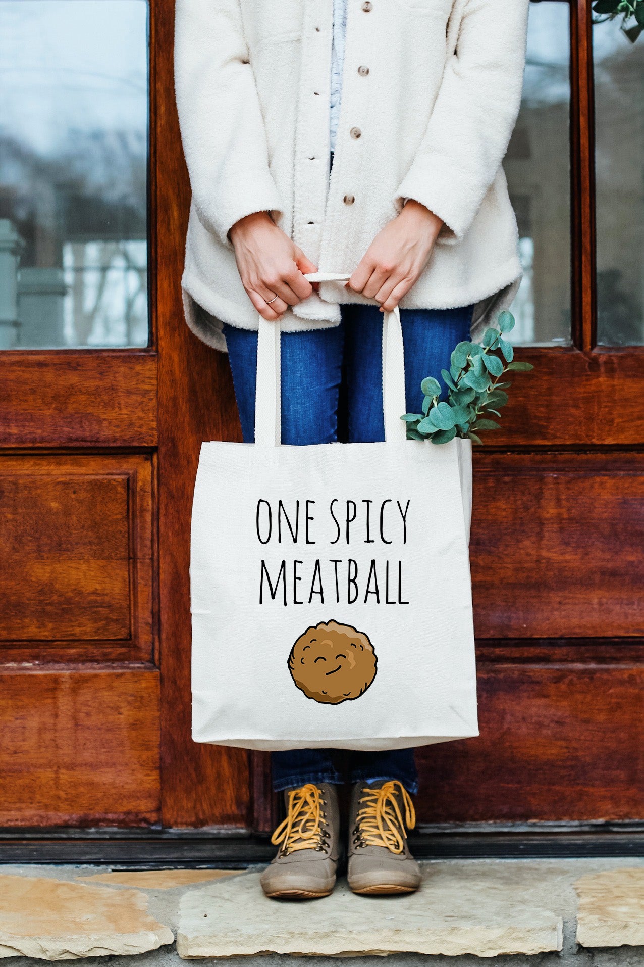 a woman holding a bag that says, one spicy meatball