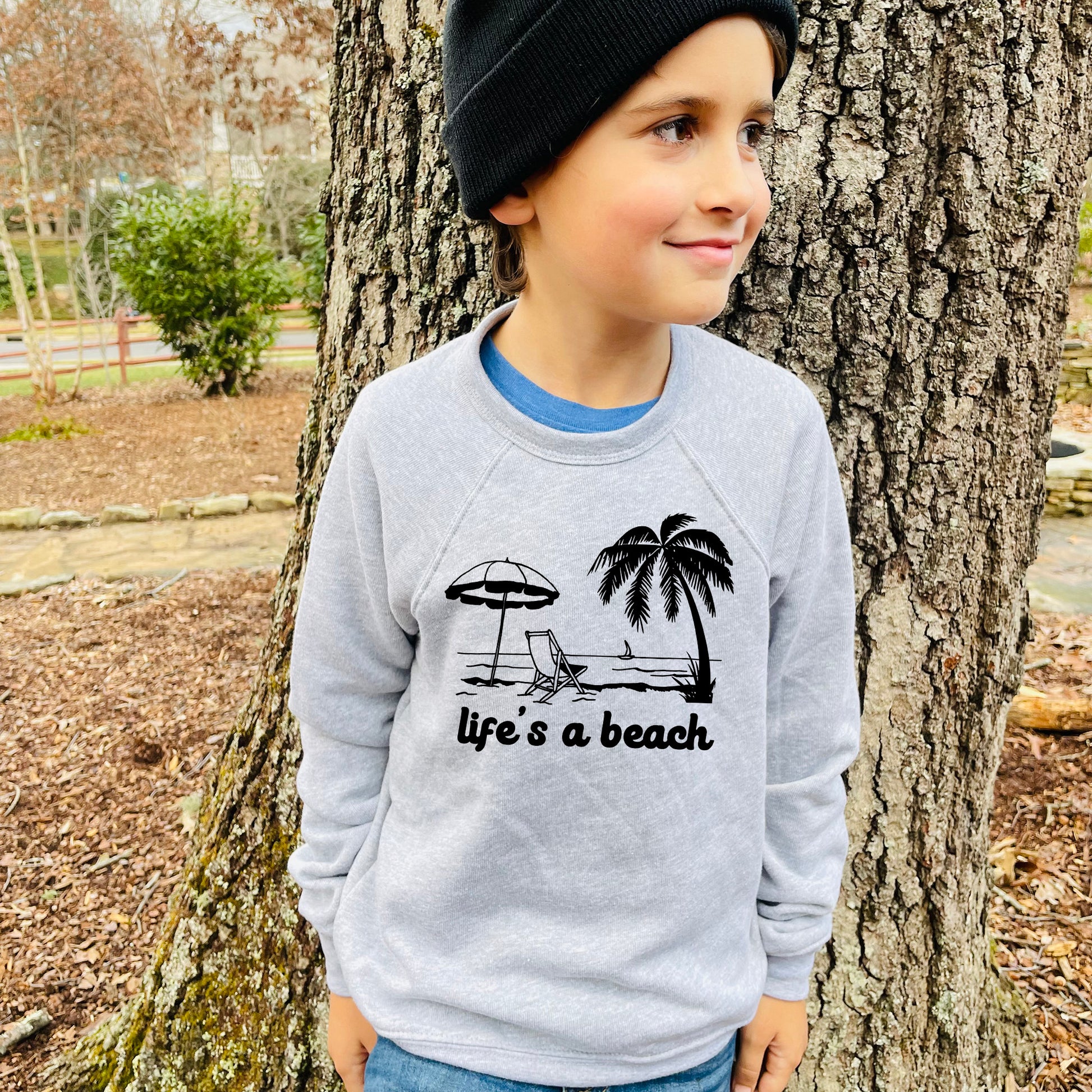 a young boy standing next to a tree