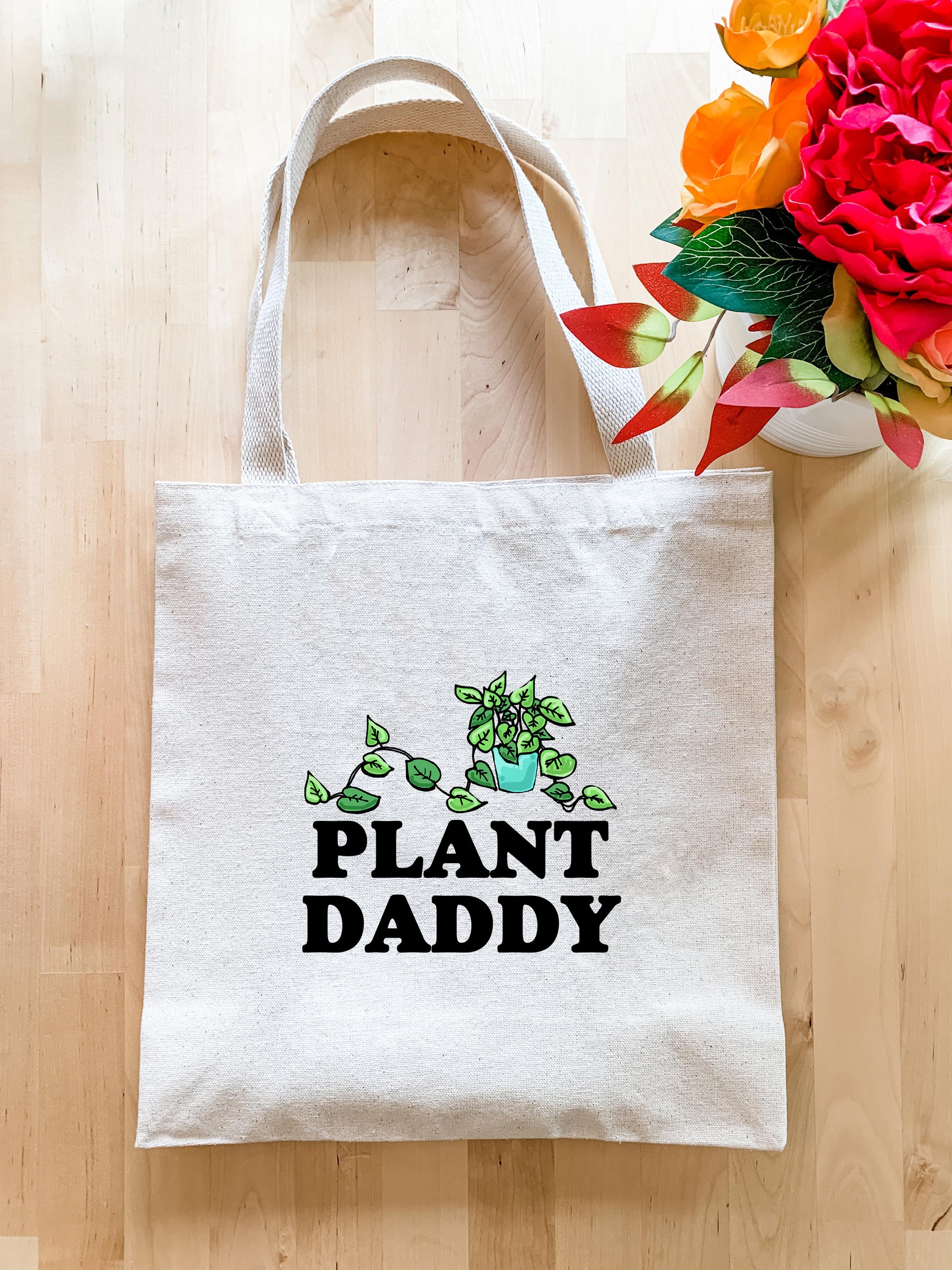 a plant daddy tote bag next to a bouquet of flowers