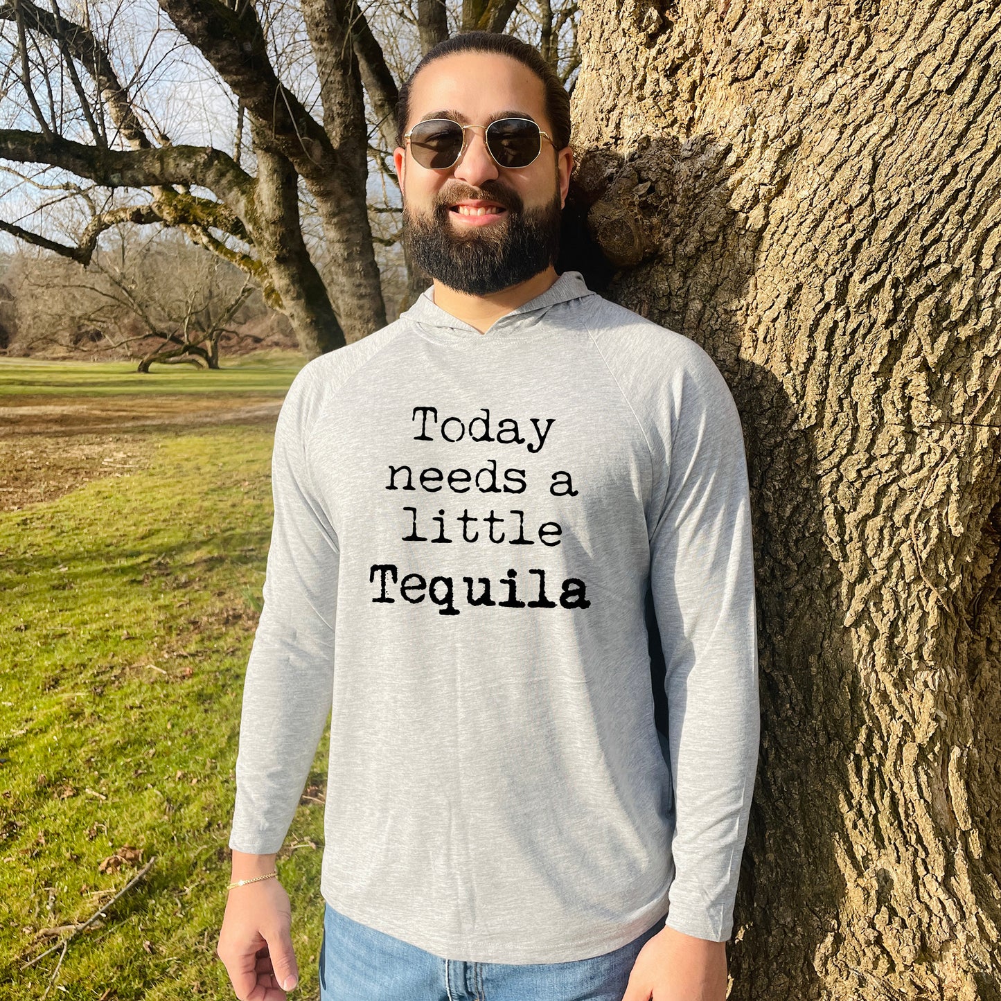 a man standing next to a tree wearing a shirt that says today needs a little