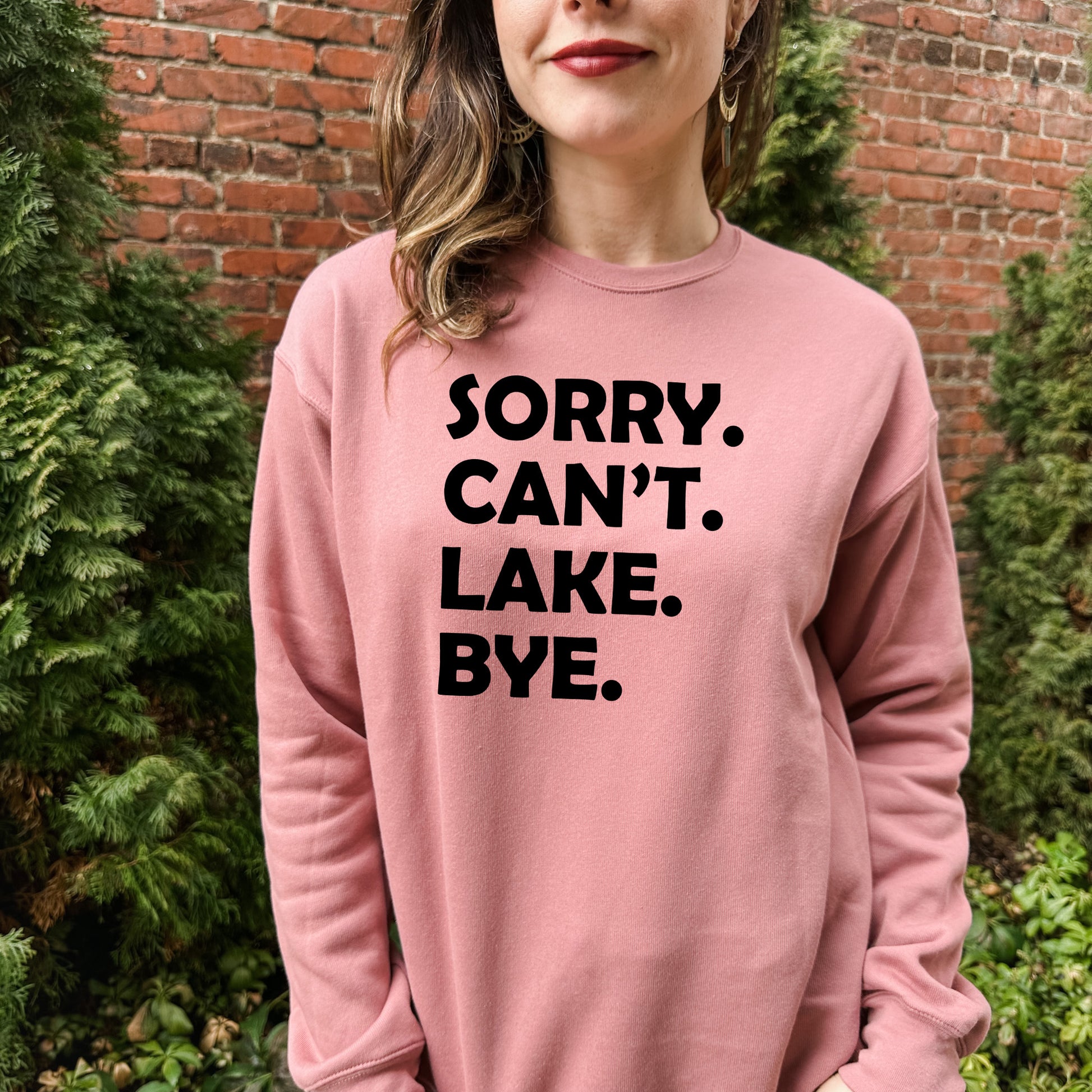 a woman wearing a pink sweatshirt that says sorry can't lake bye