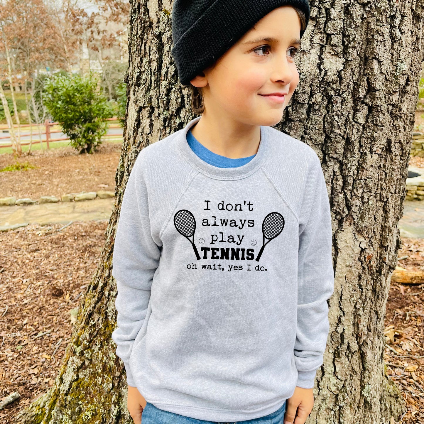 a young boy standing next to a tree