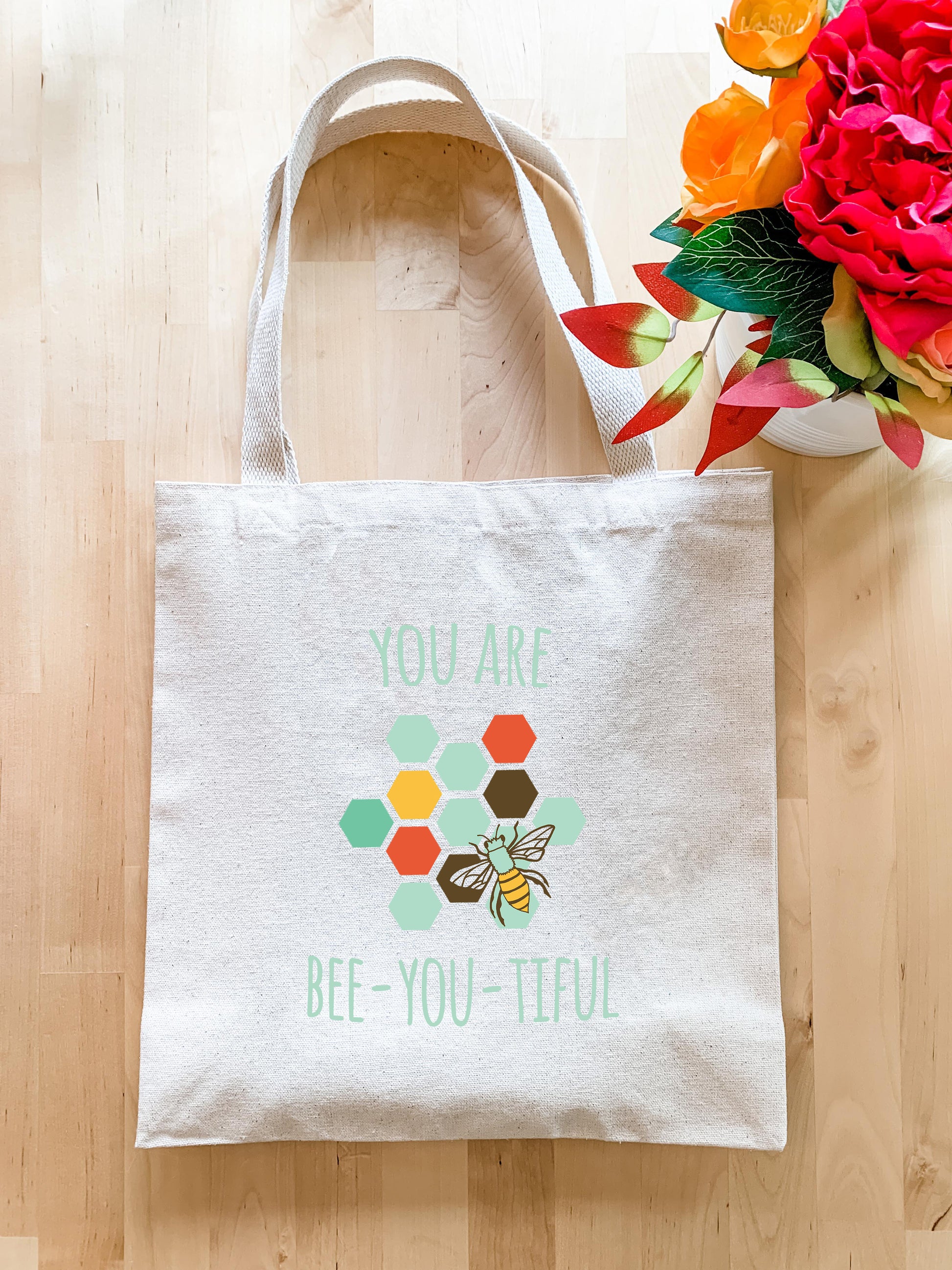 a white tote bag with a bee you - tiful design