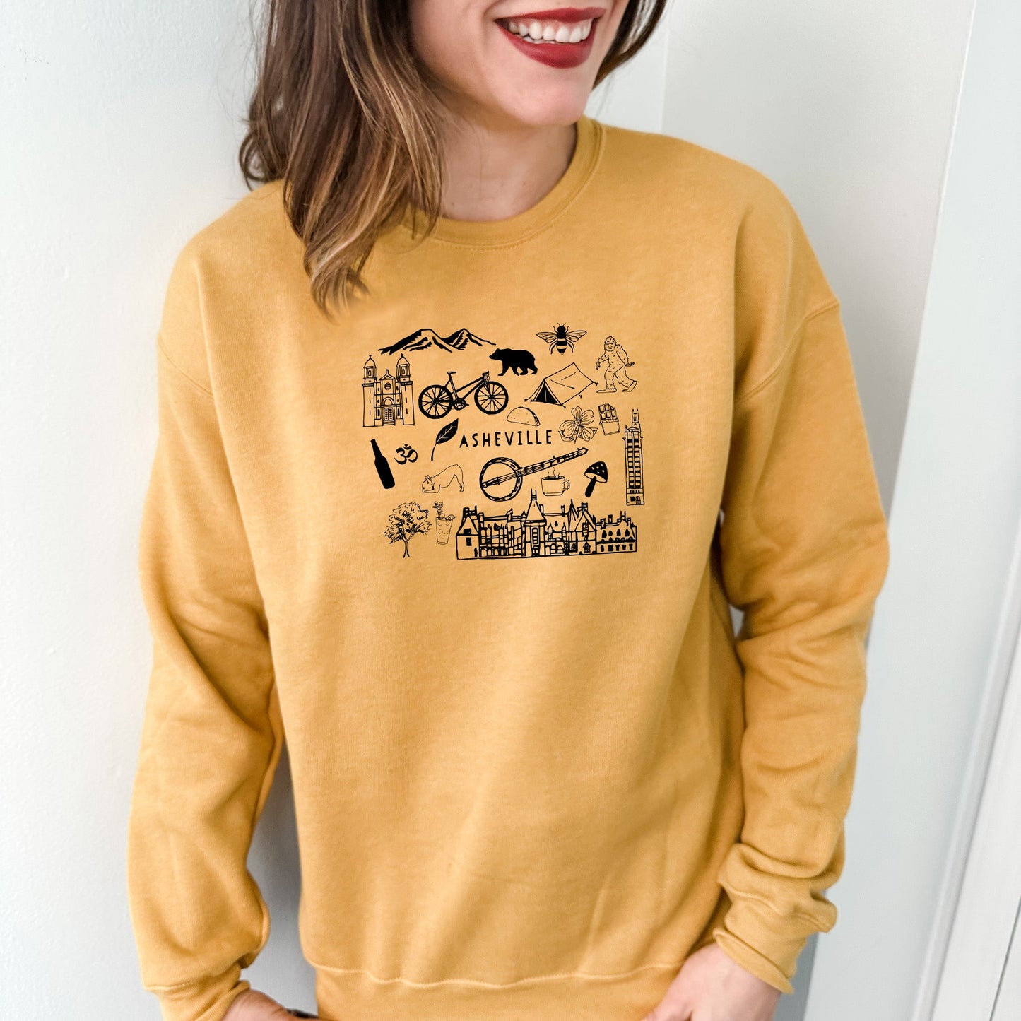 a woman wearing a yellow sweatshirt with a picture of a bike and mountains on it