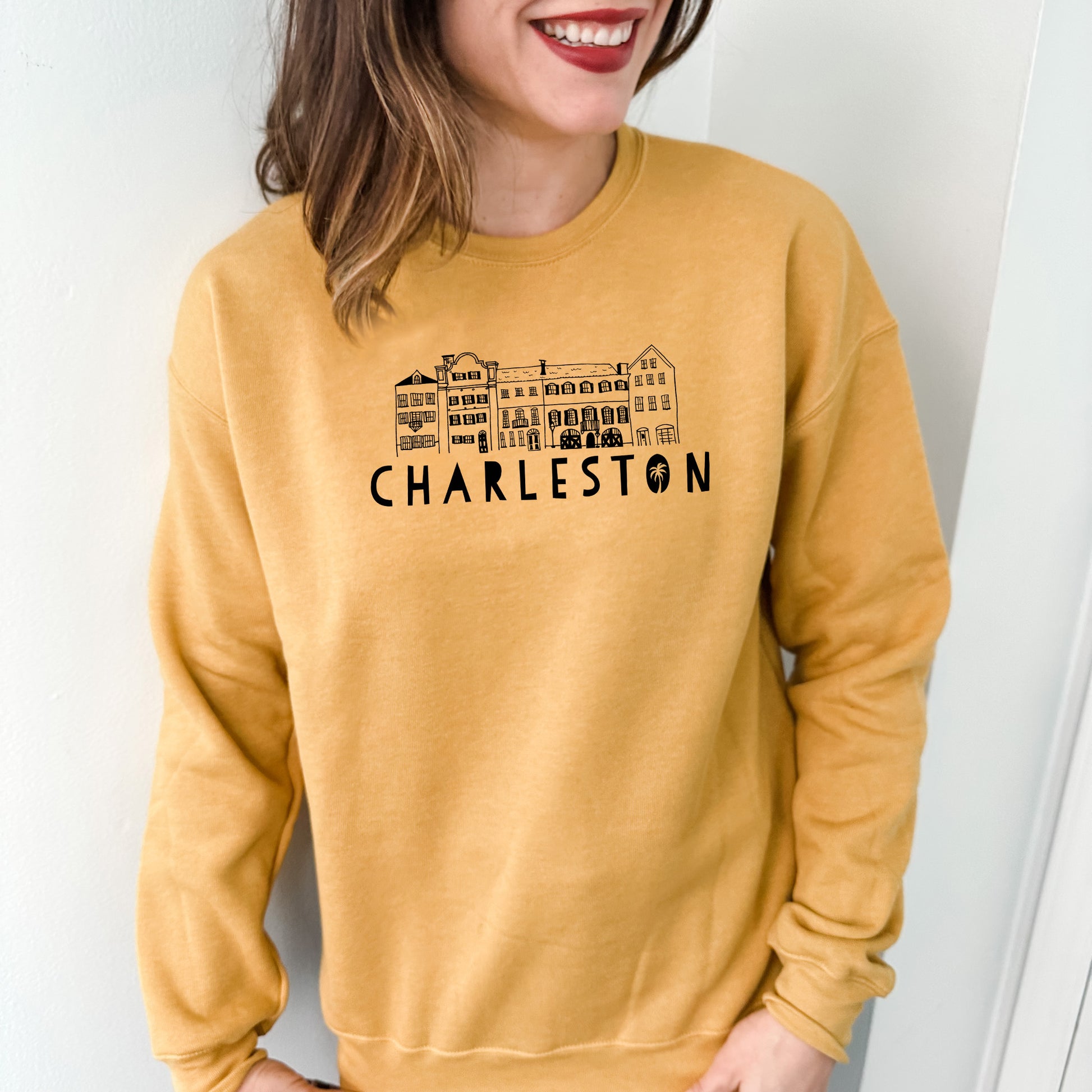 a woman wearing a yellow sweatshirt with a picture of charleston on it