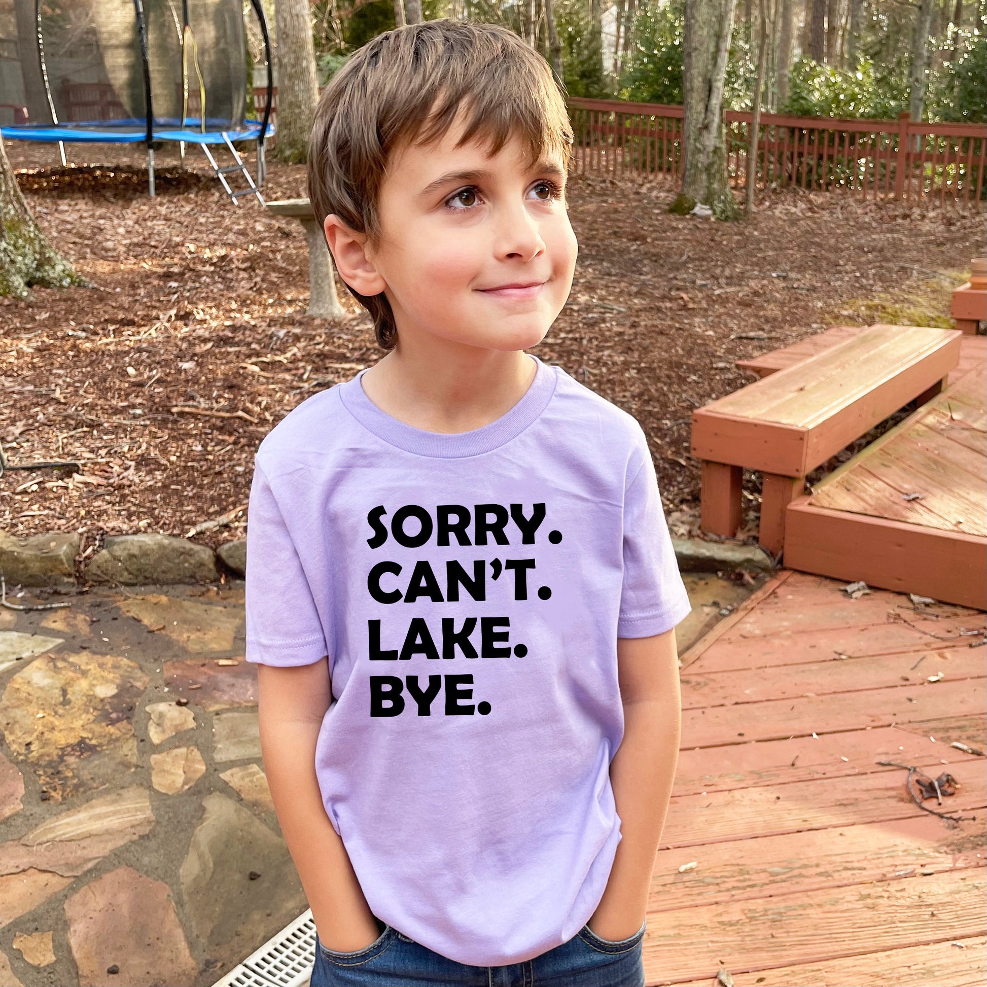 a young boy wearing a purple shirt that says sorry, can't lake bye