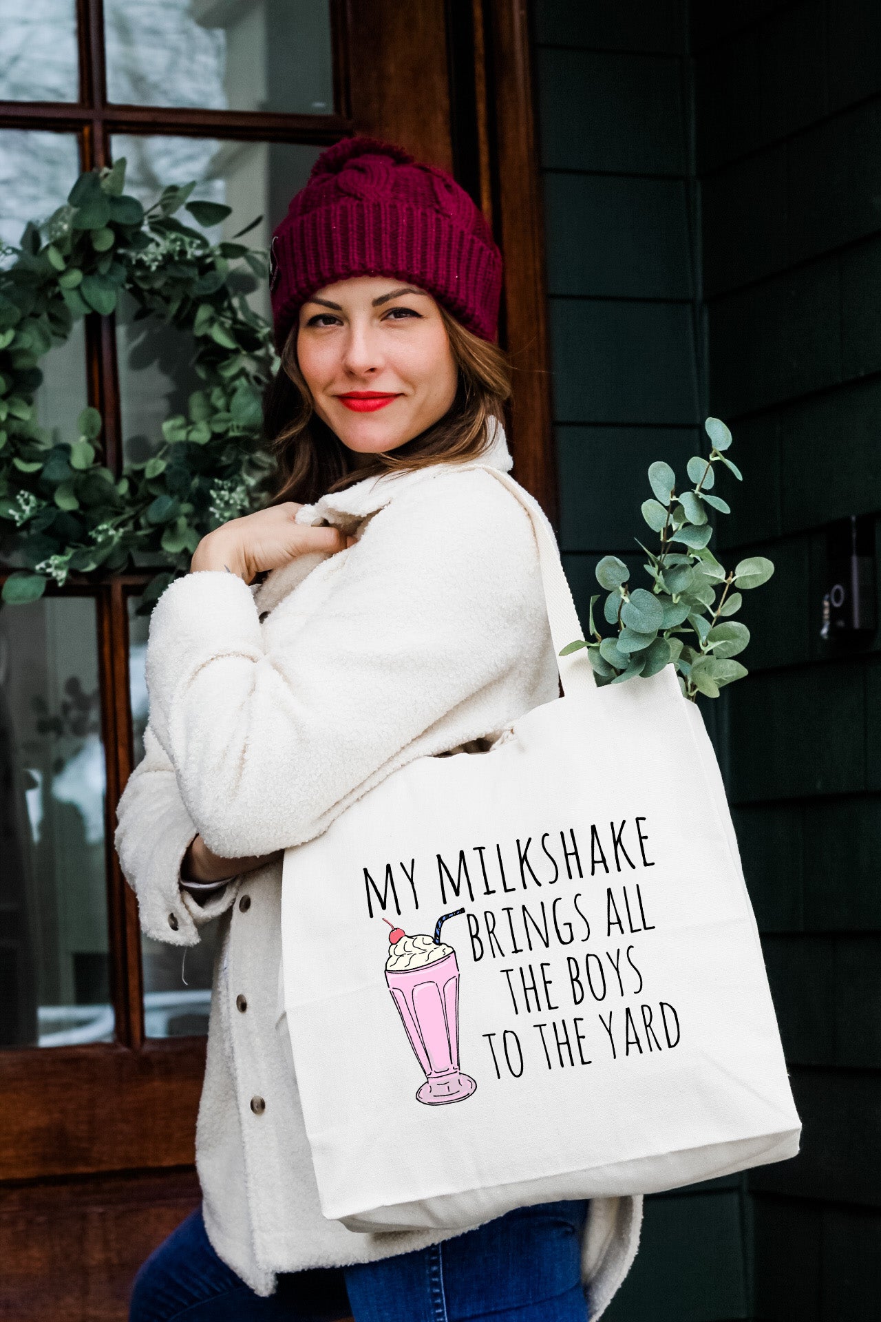 a woman carrying a bag that says, my milkshake brings all the boys