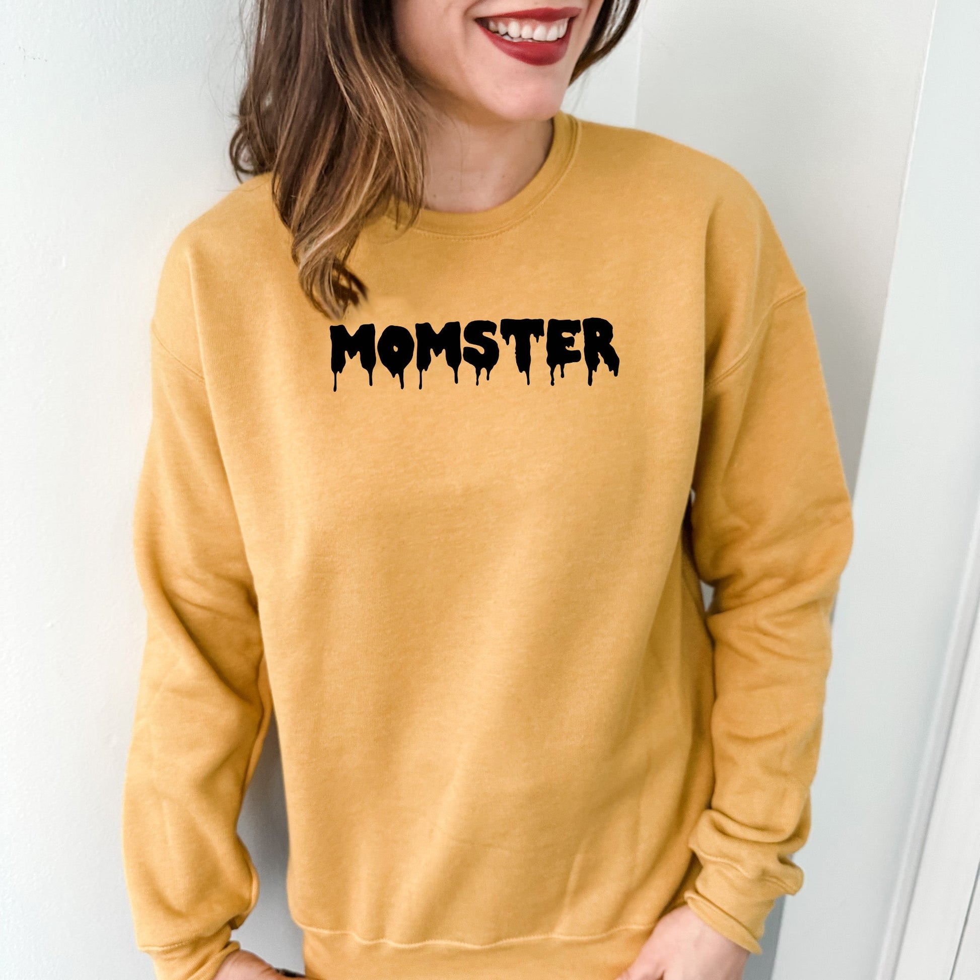 a woman wearing a yellow sweatshirt with the word monster on it