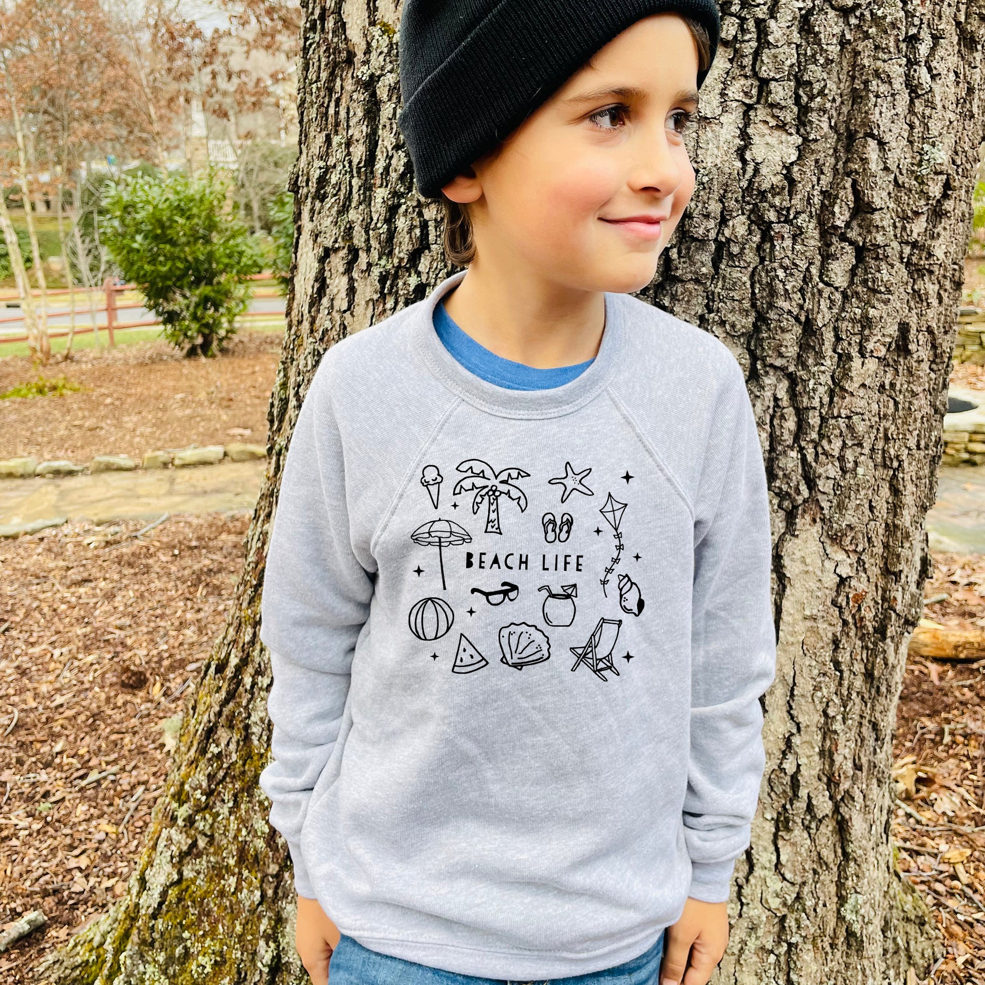 a young boy standing in front of a tree