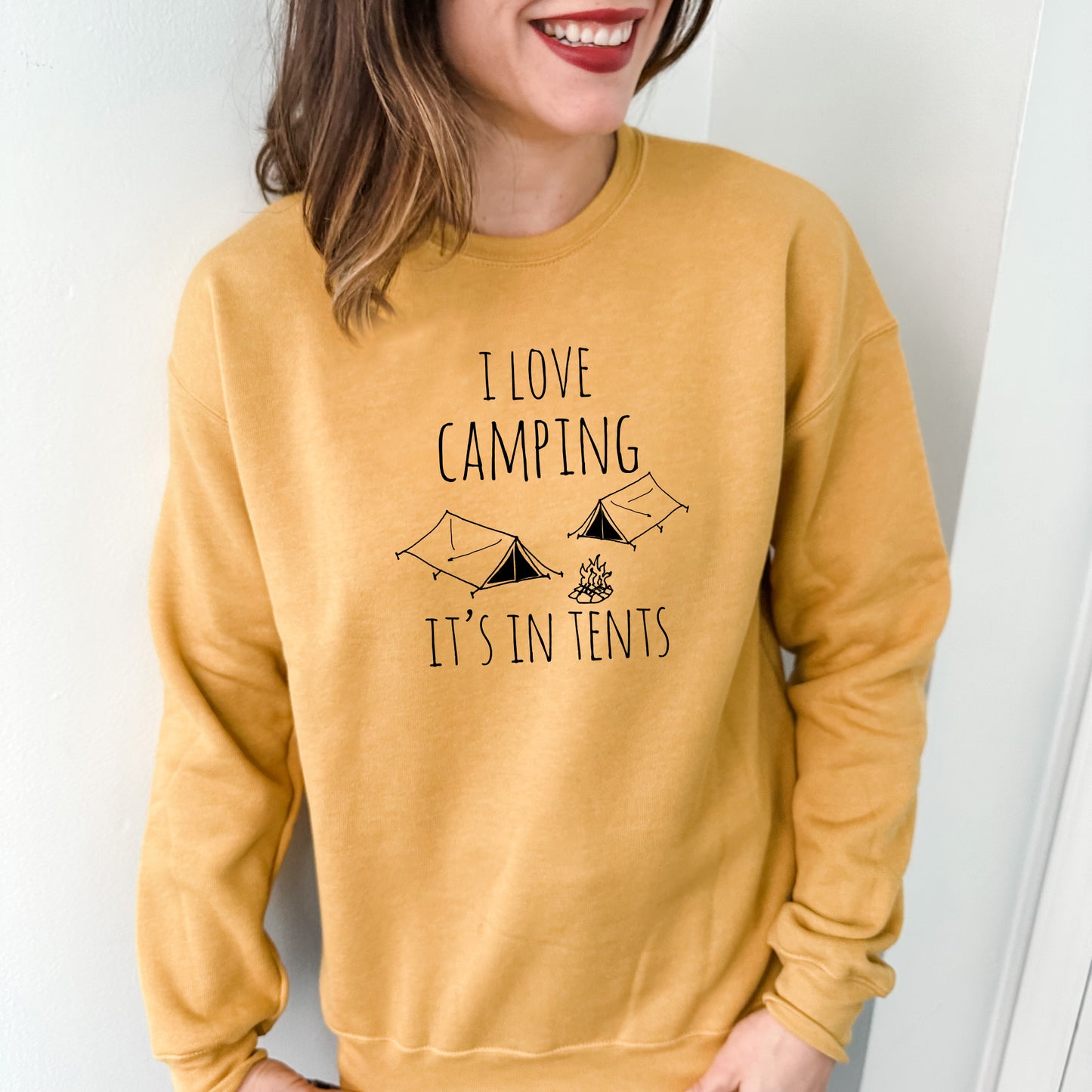 a woman wearing a sweatshirt that says i love camping it's in tents