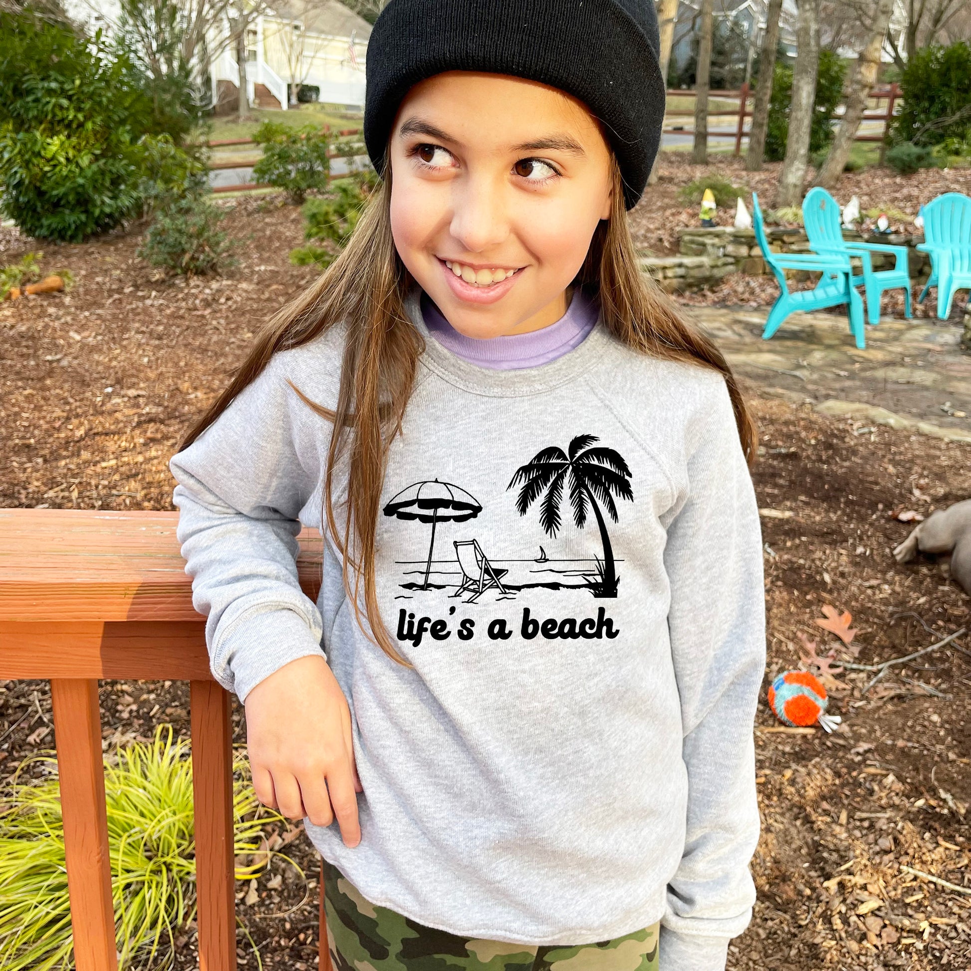 a young girl wearing a life's a beach shirt