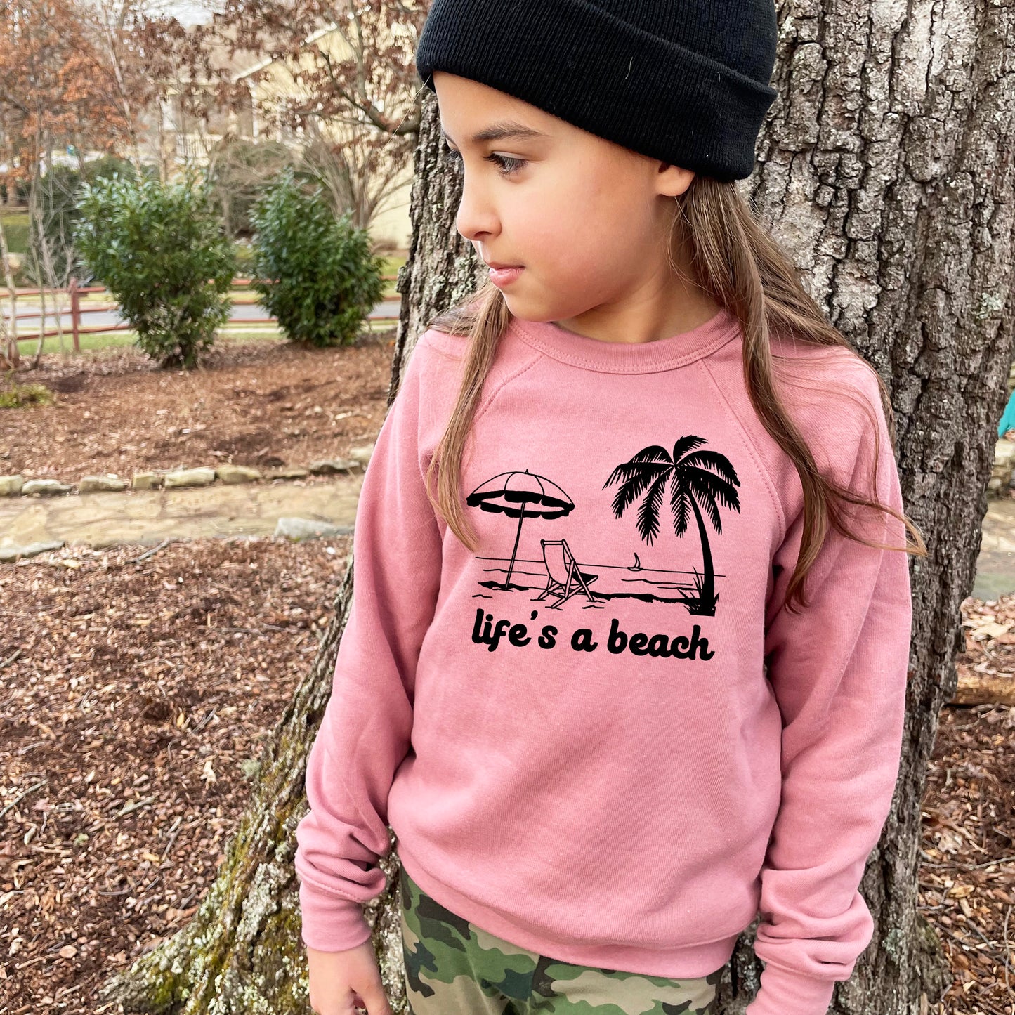 a little girl standing next to a tree