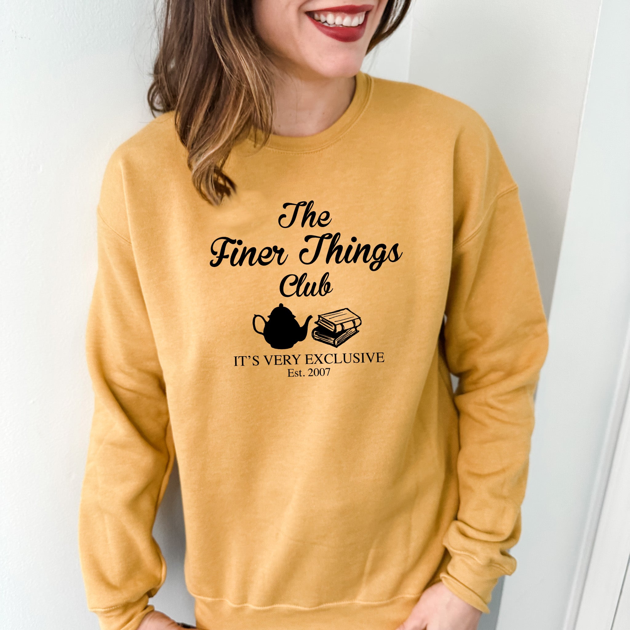 a woman wearing a sweatshirt that says the finer things club it's very